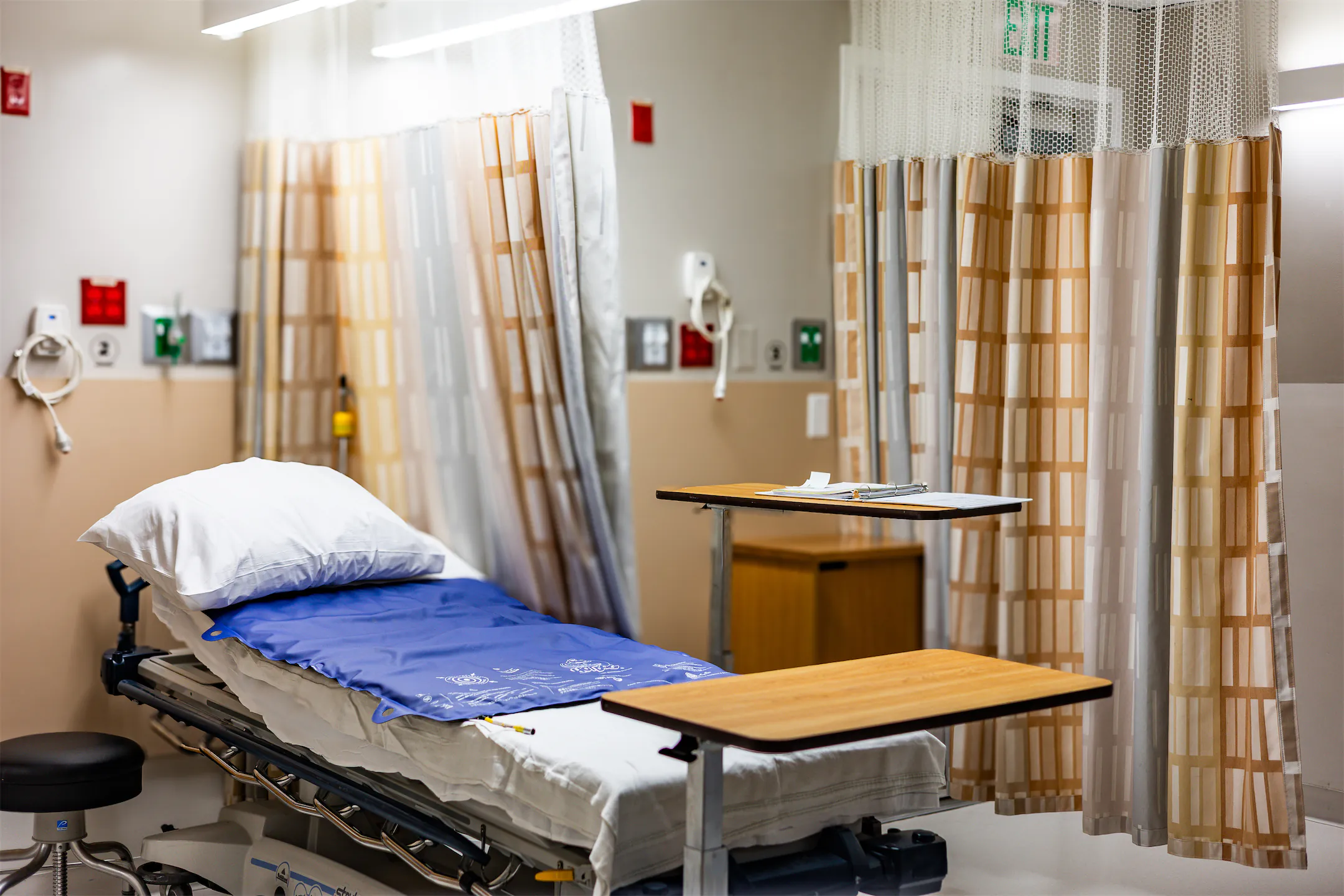 Recovery bay with a patient bed, overbed table, and privacy curtains