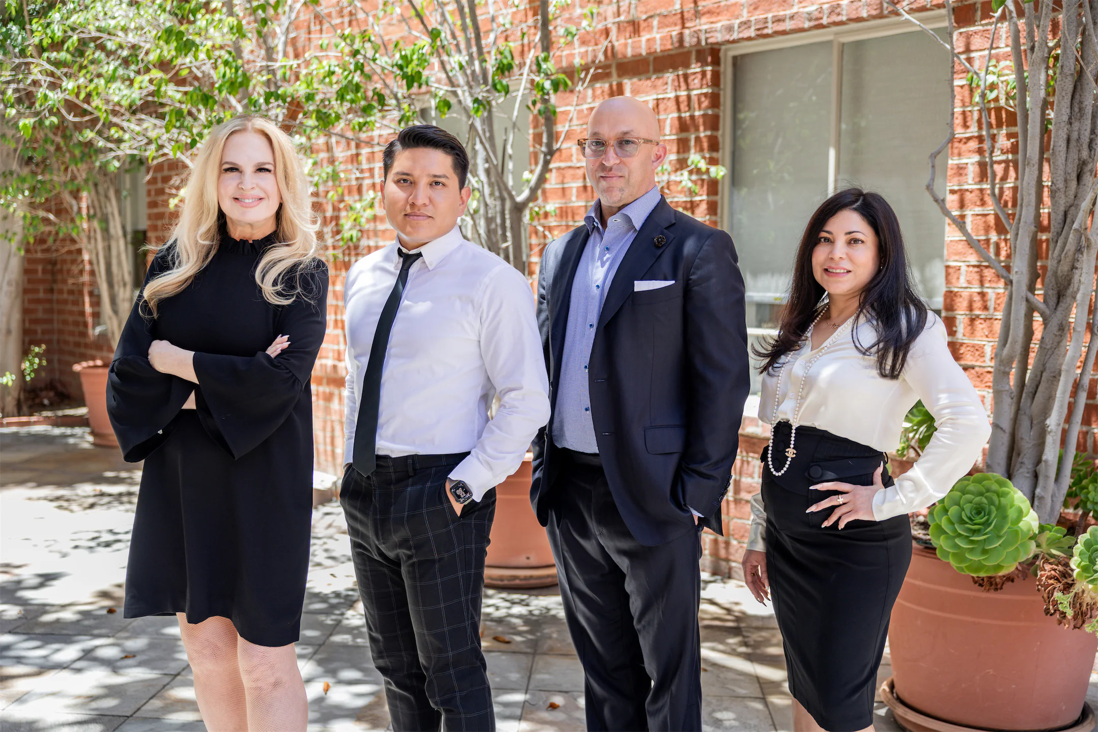 Four GVMD team members posed in a brick courtyard on a sunny day