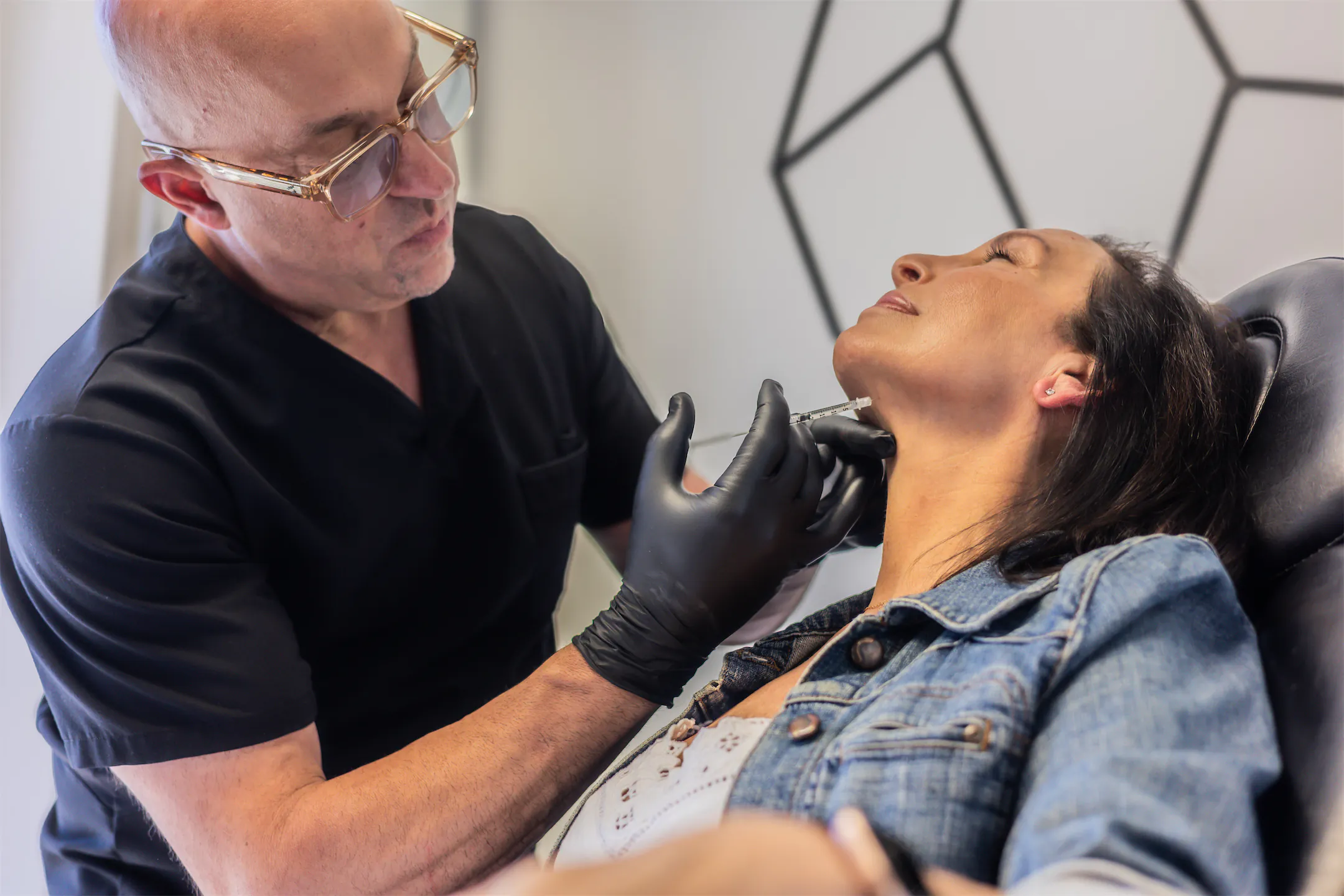 Dr. Vallecillos treating a patient's jawline as she rests with eyes closed