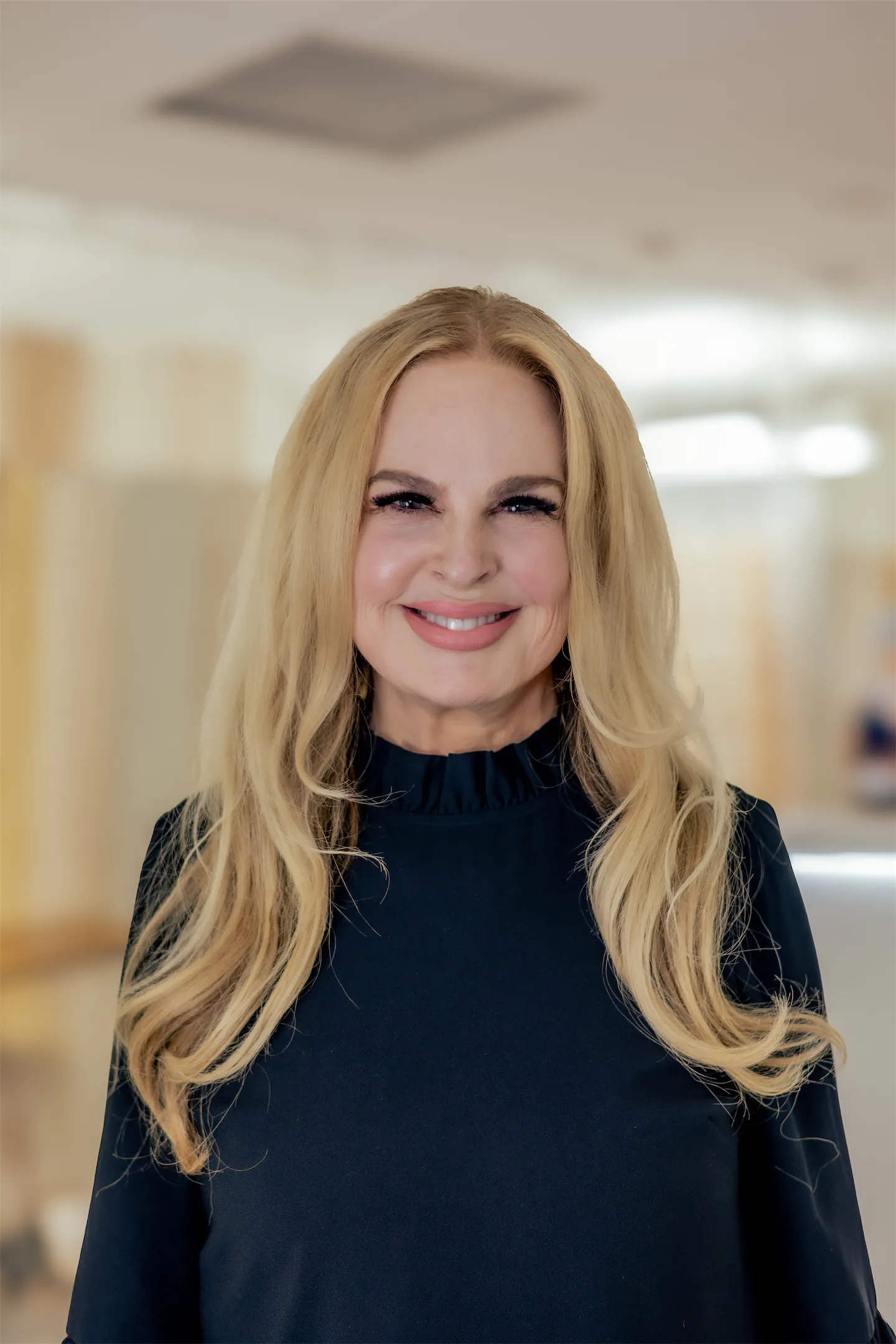 Smiling staff member with long blonde hair in a navy ruffle-neck top in the GVMD office