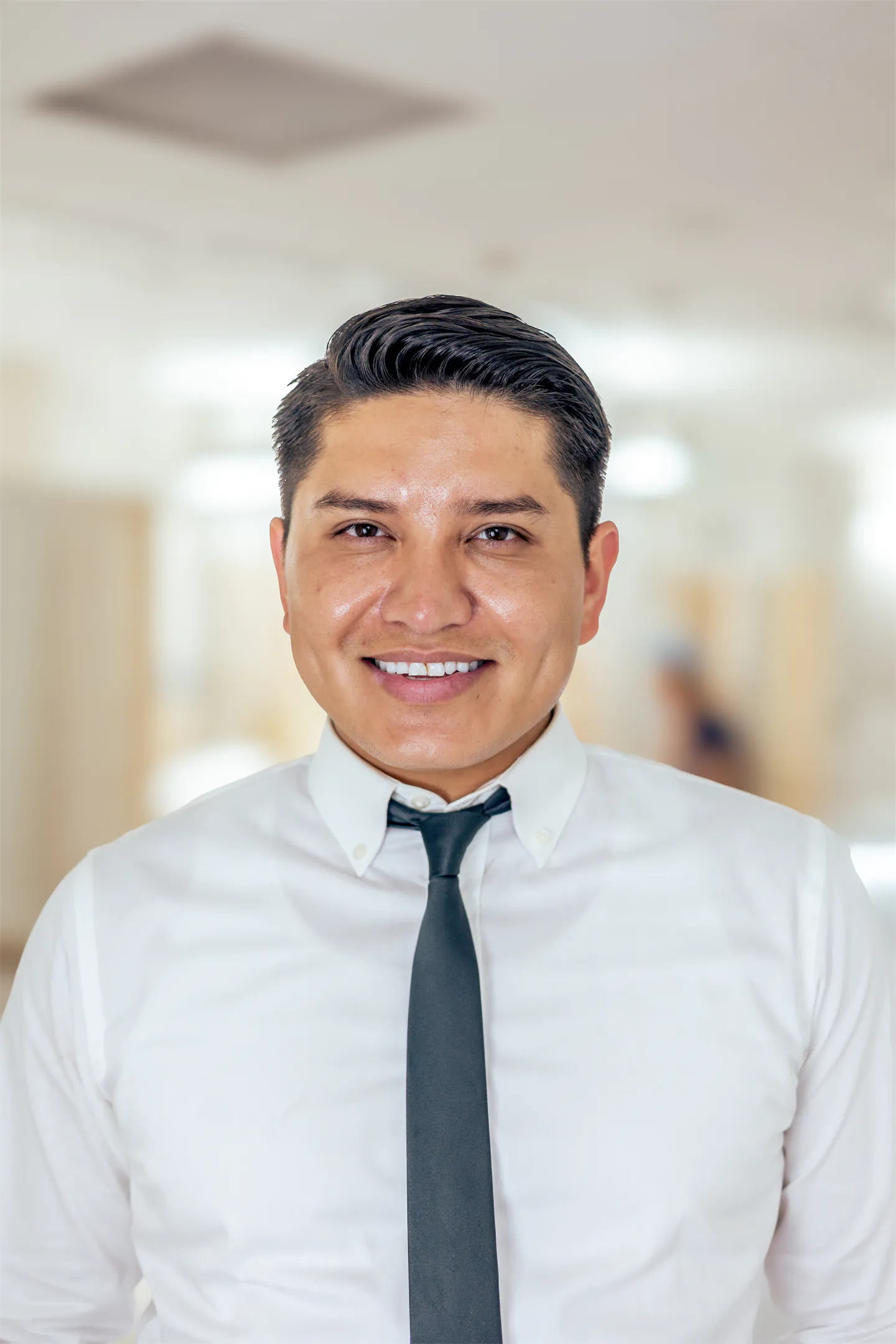 Angel Duenas smiling in a white shirt and dark tie in the GVMD office