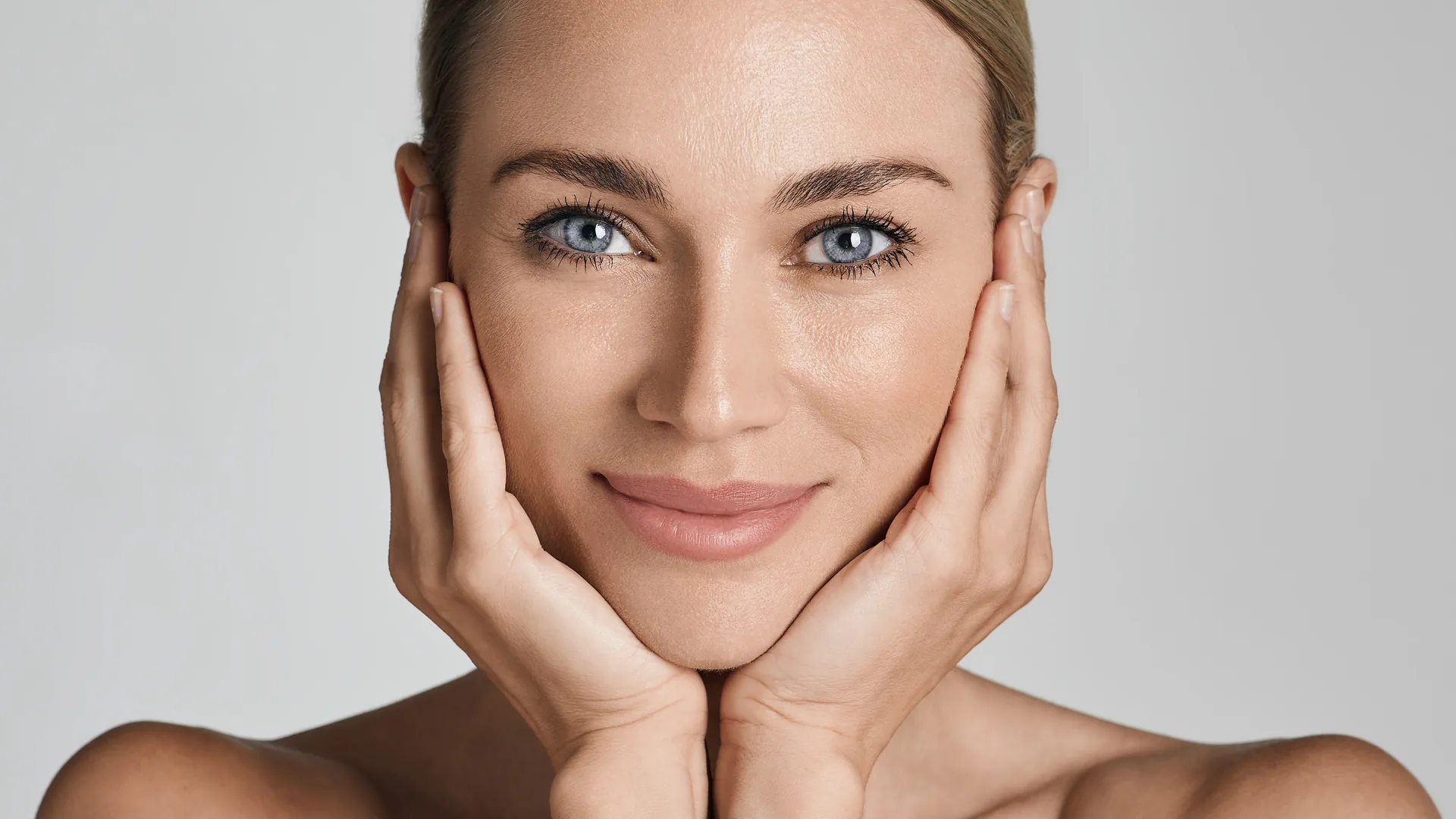 Smiling woman with blue eyes resting her face in both hands
