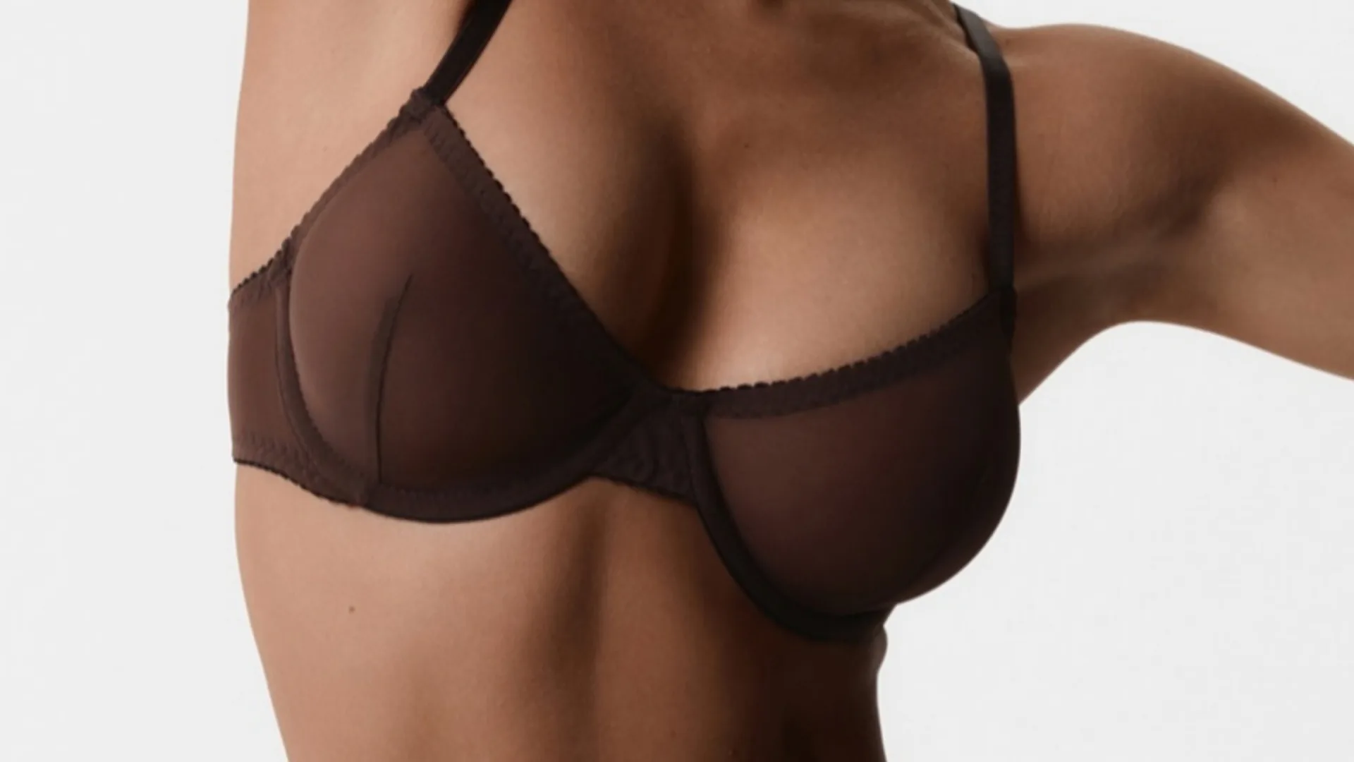 Close-up of a woman's chest in a sheer brown bra