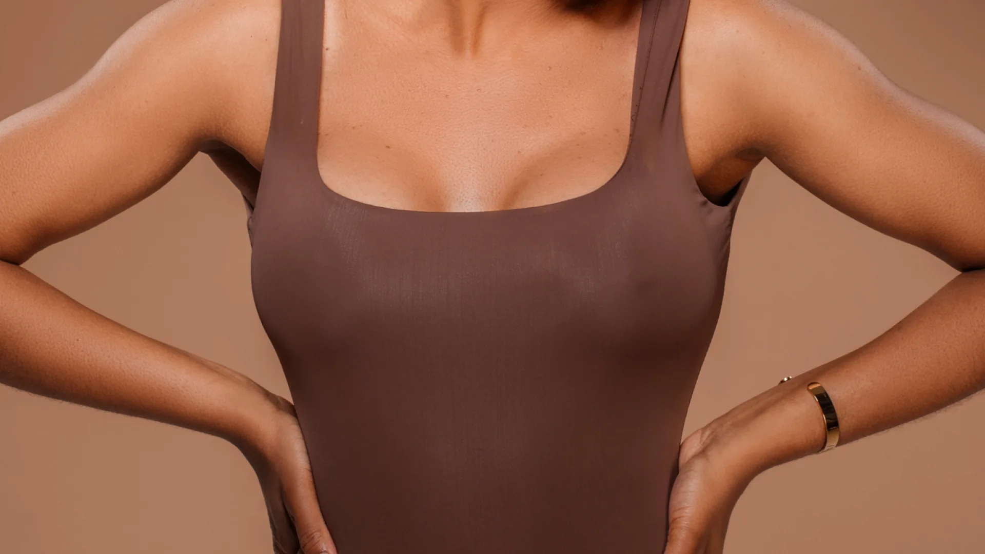 Woman in a brown tank top with her hands on her hips