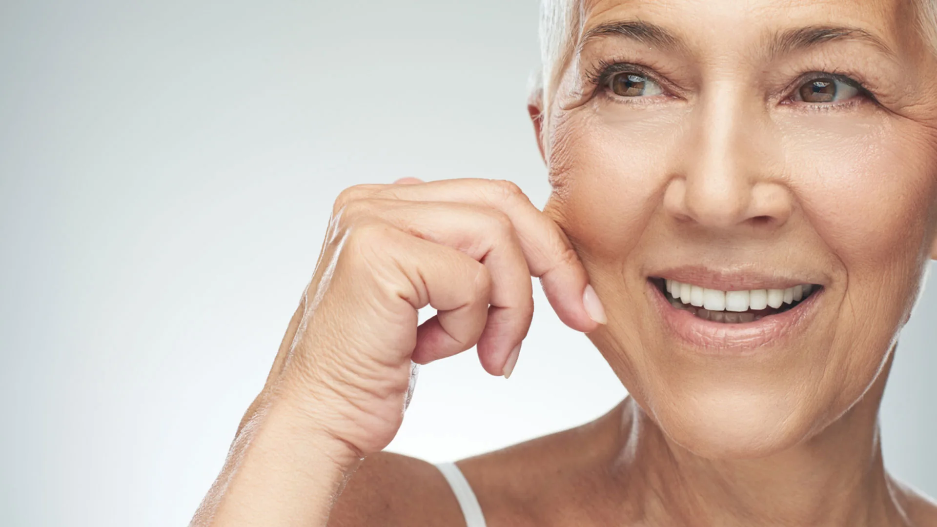 Smiling older woman touching her cheek