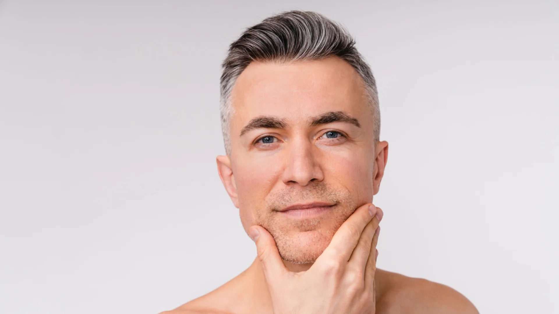 Gray-haired man resting his chin on his hand and looking at the camera