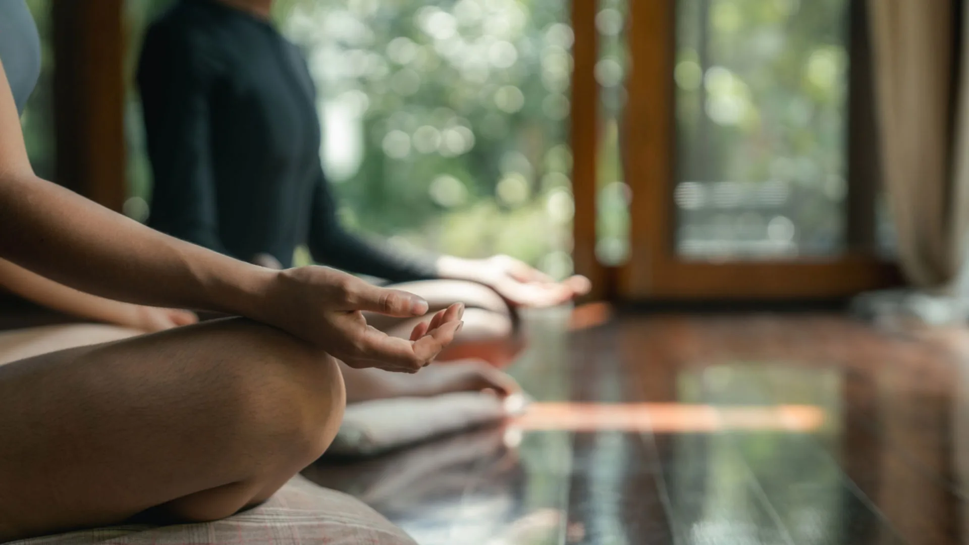 People seated cross-legged in a meditation pose on a wooden floor
