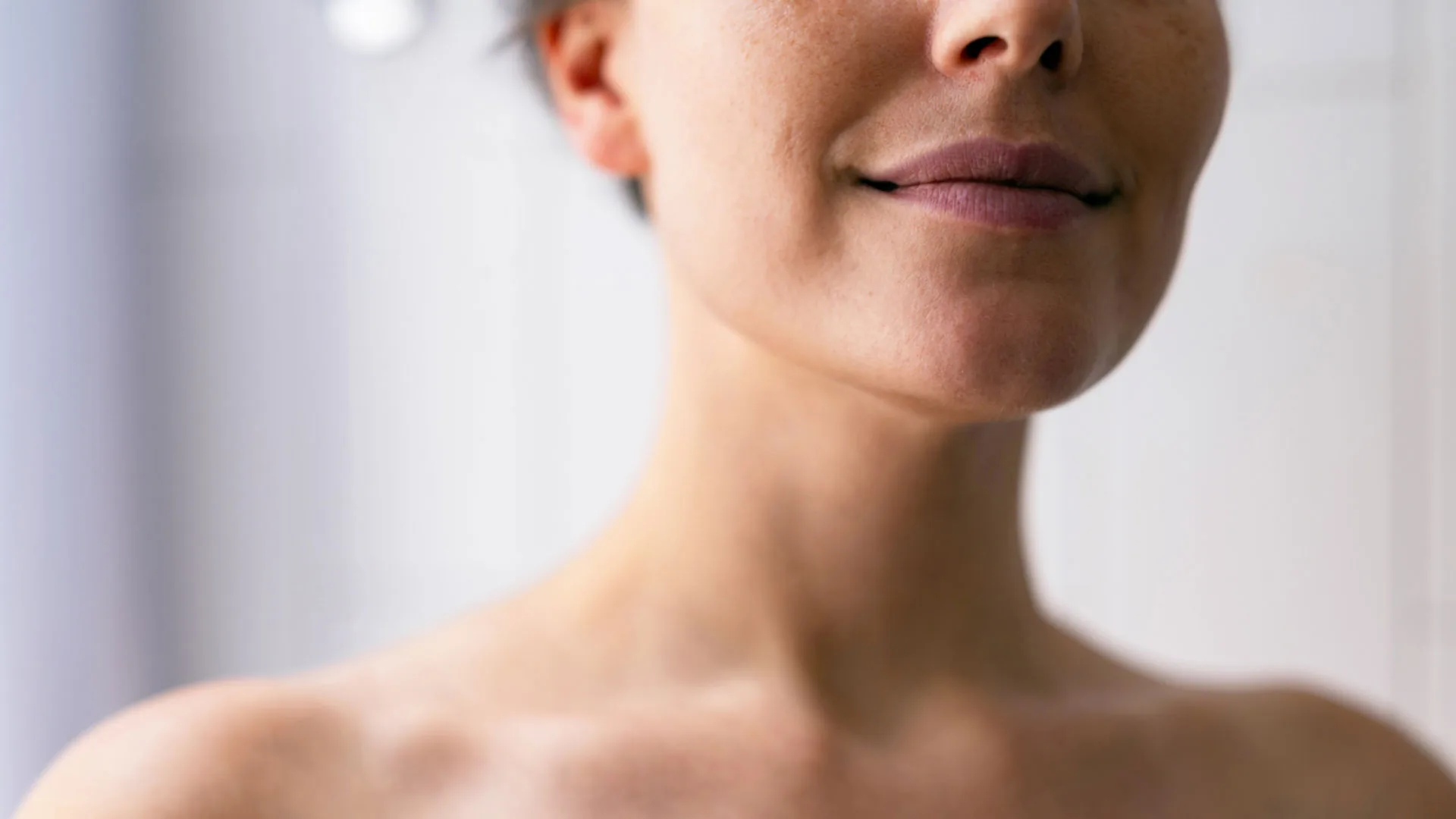 Smiling woman's lower face, neck, and collarbones, eyes out of frame
