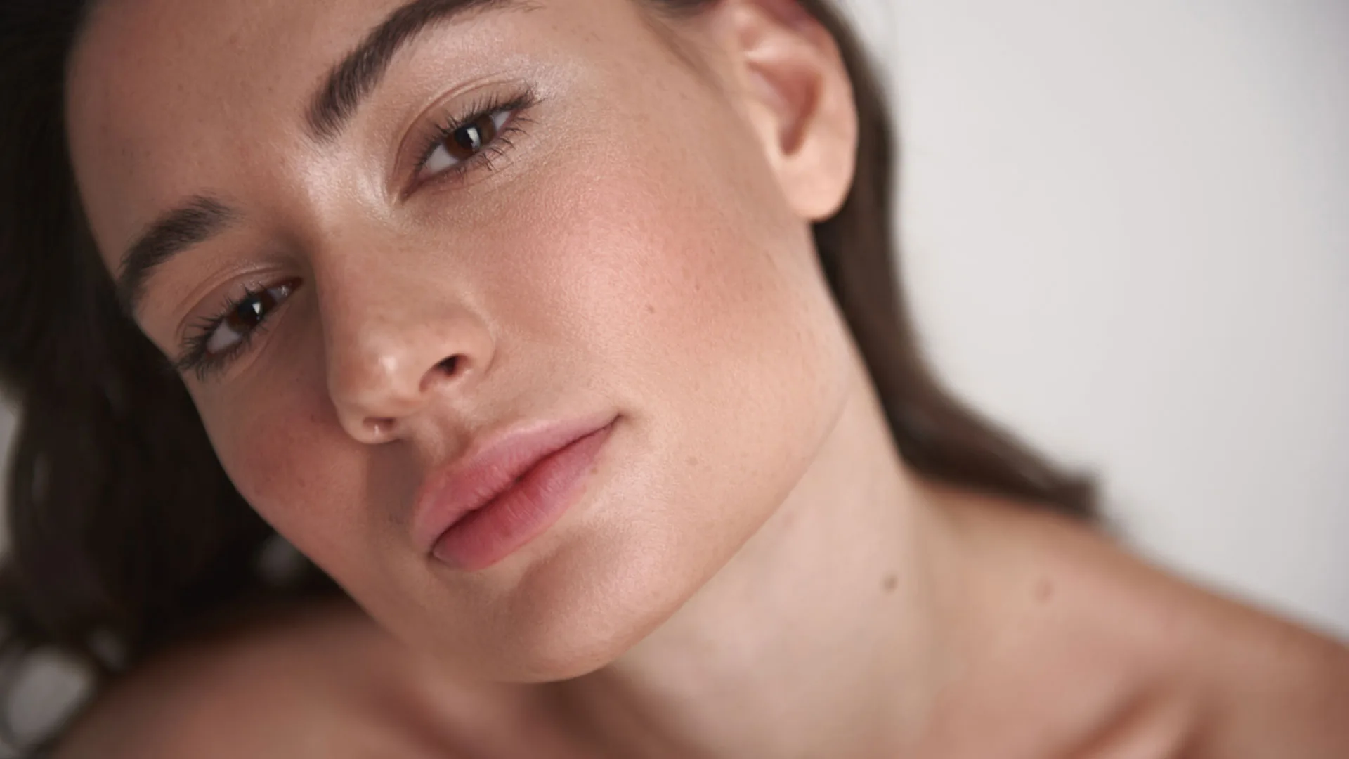 Woman tilting her head, showing her cheekbones and jawline in soft light