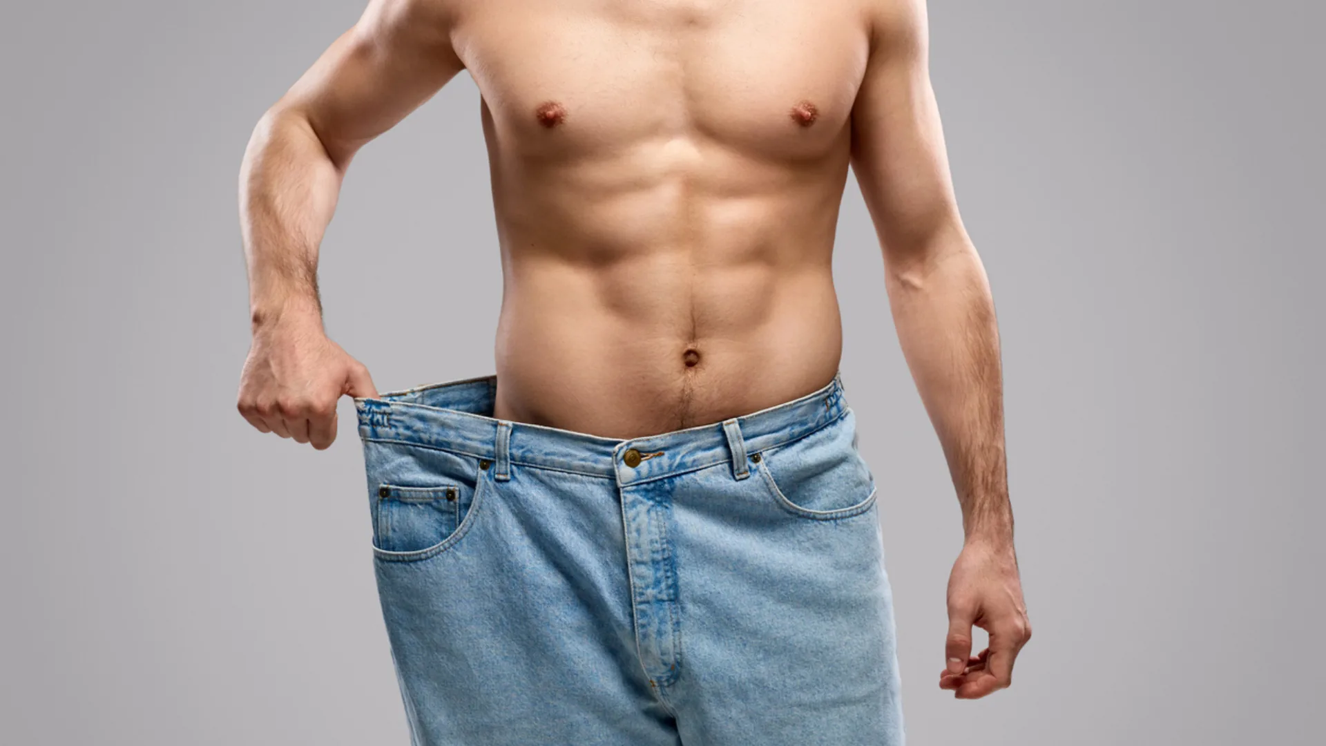 Shirtless man holding out the waistband of oversized jeans