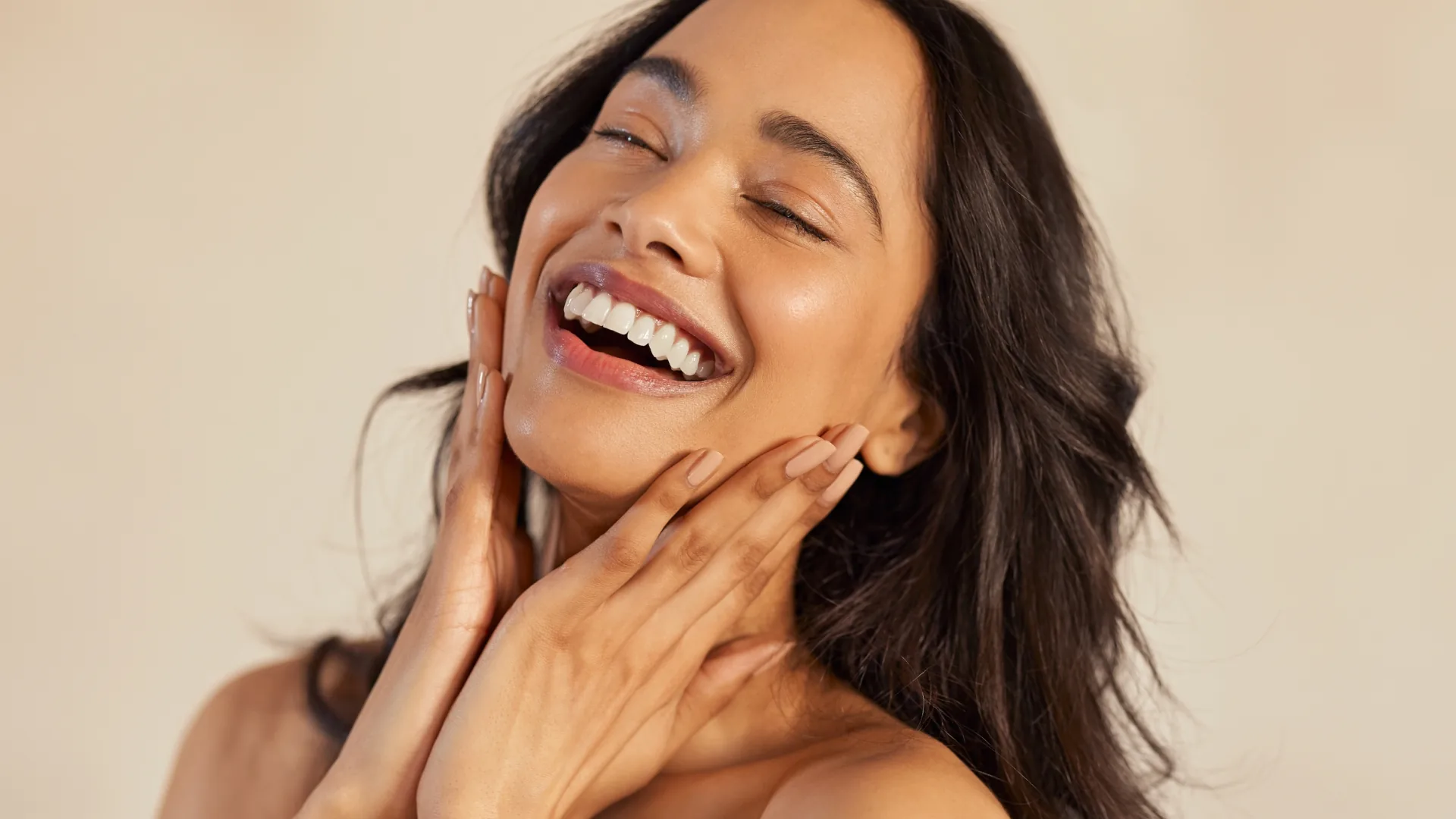 Laughing woman with eyes closed and hands on her face