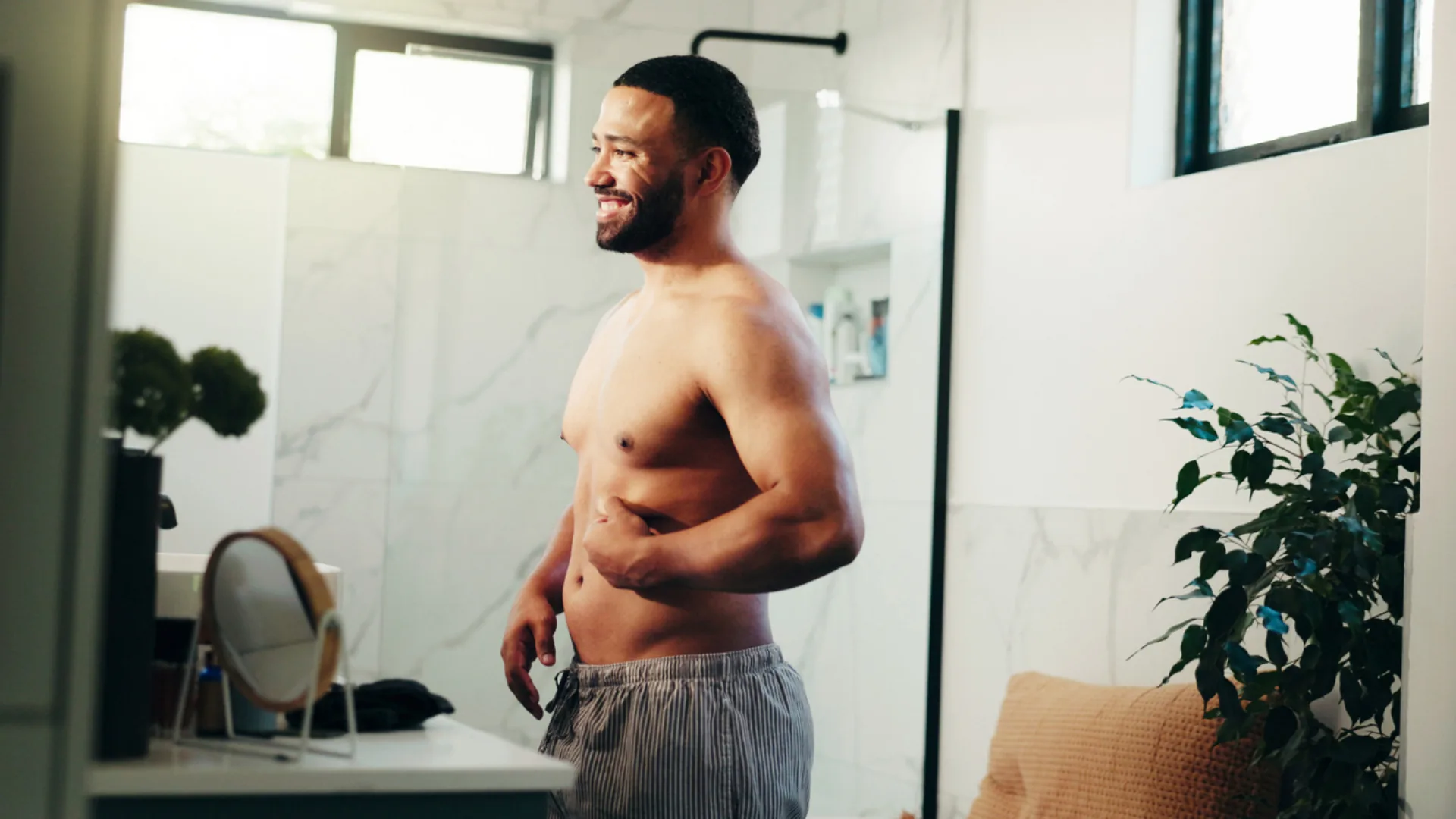 Smiling shirtless man standing in a bright bathroom