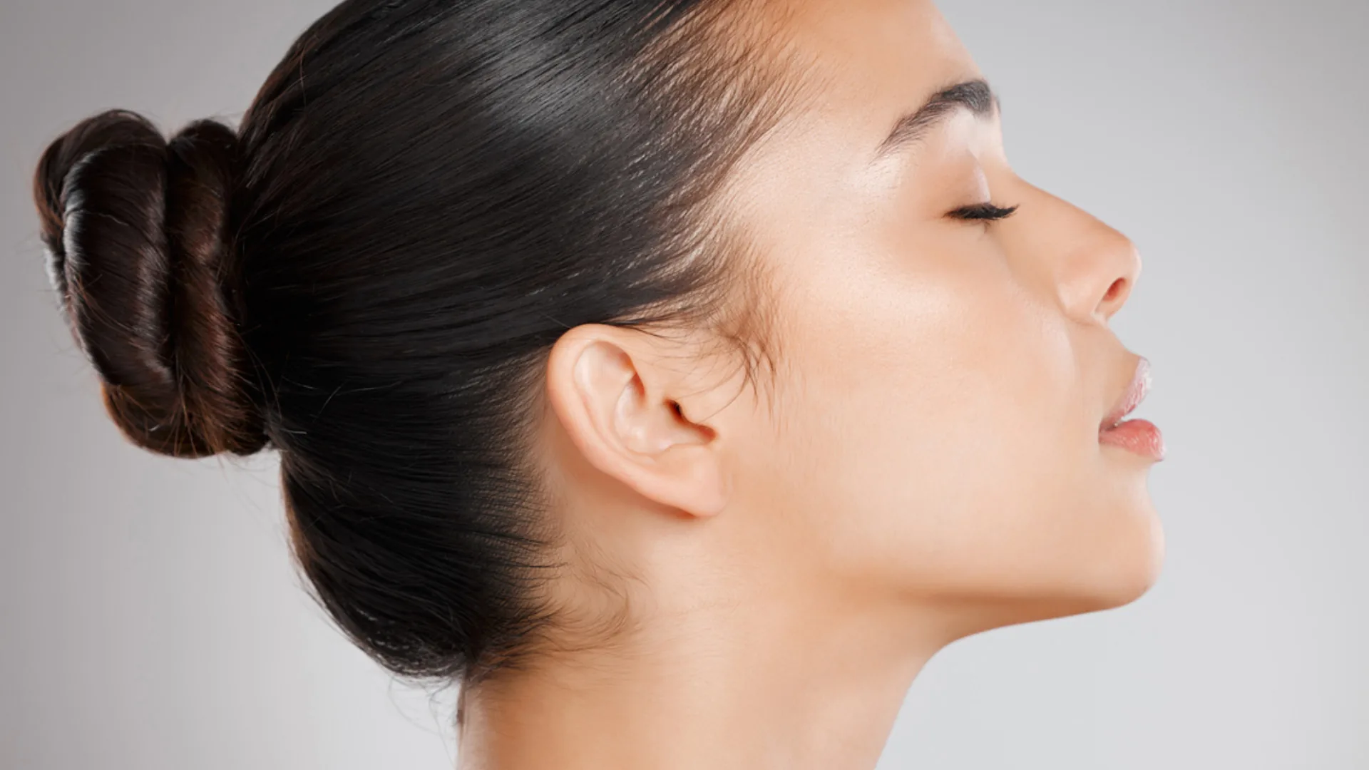 Woman in profile with eyes closed and hair in a bun, chin lifted