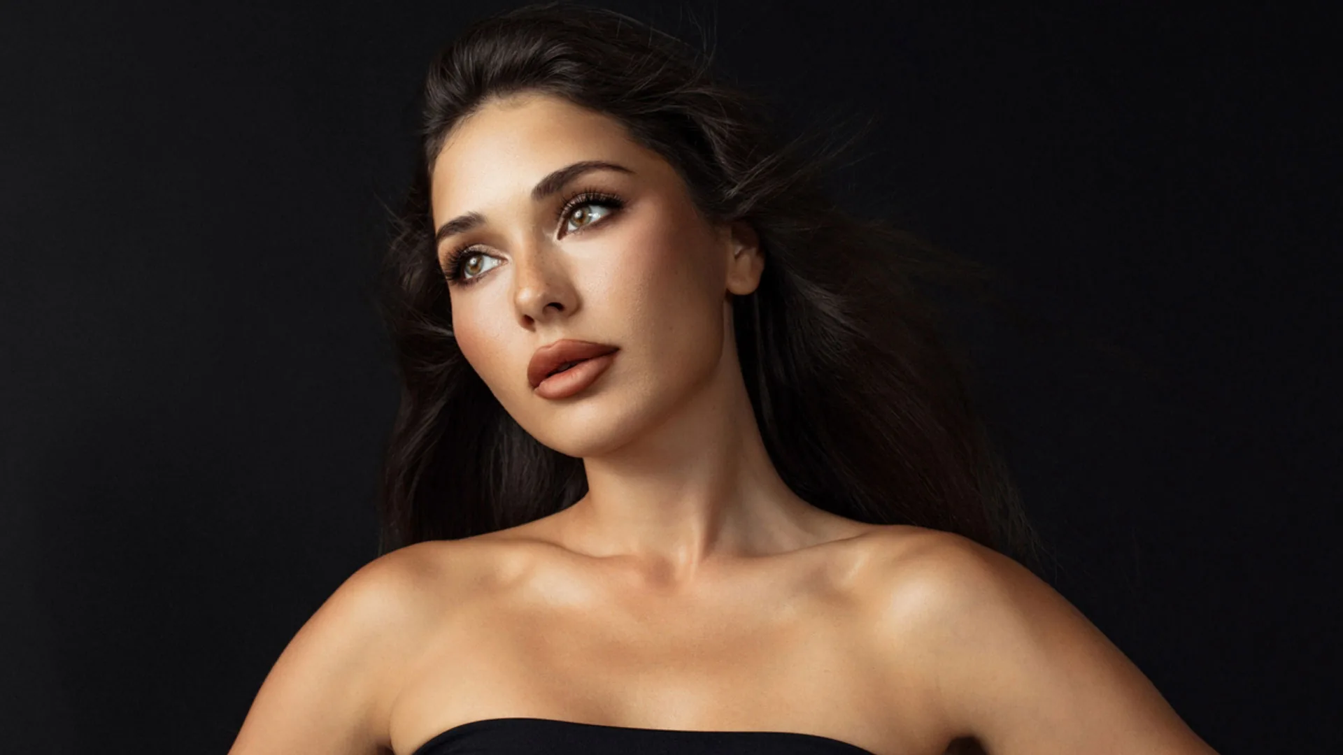 Woman with long dark hair and a defined jawline looking up and to the side