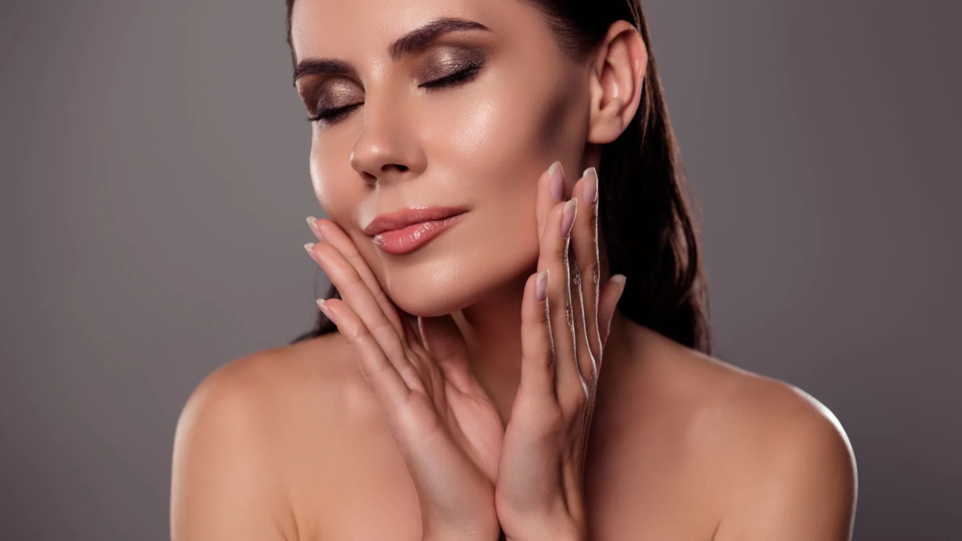 Woman with eyes closed cradling her jawline with both hands