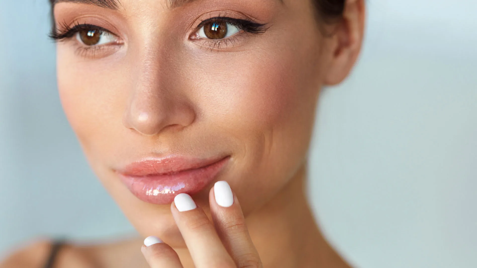 Close-up of a woman touching her glossy lower lip