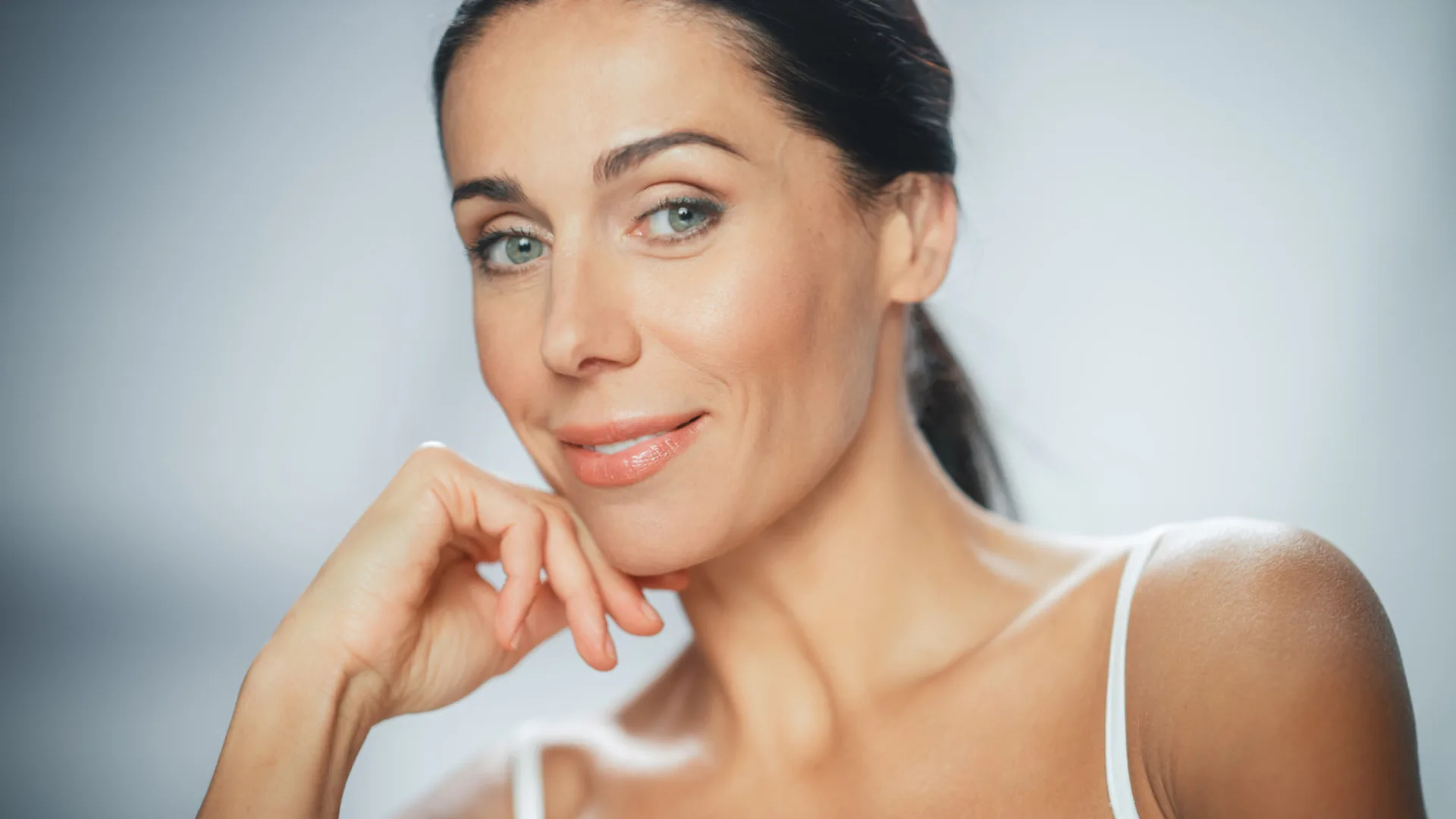 Smiling woman with dark hair pulled back, resting her chin on her hand