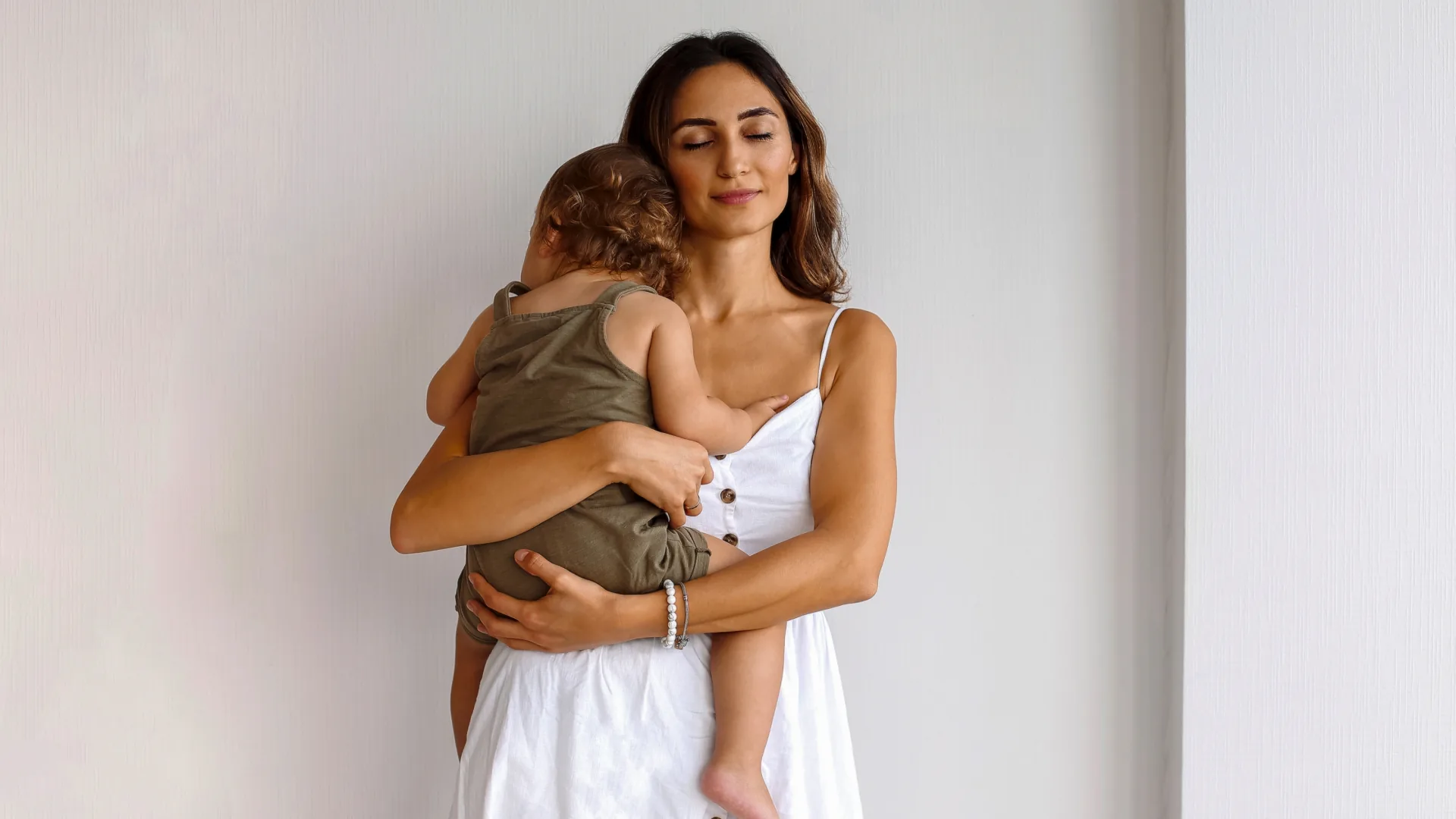 Woman in a white sundress holding her toddler close