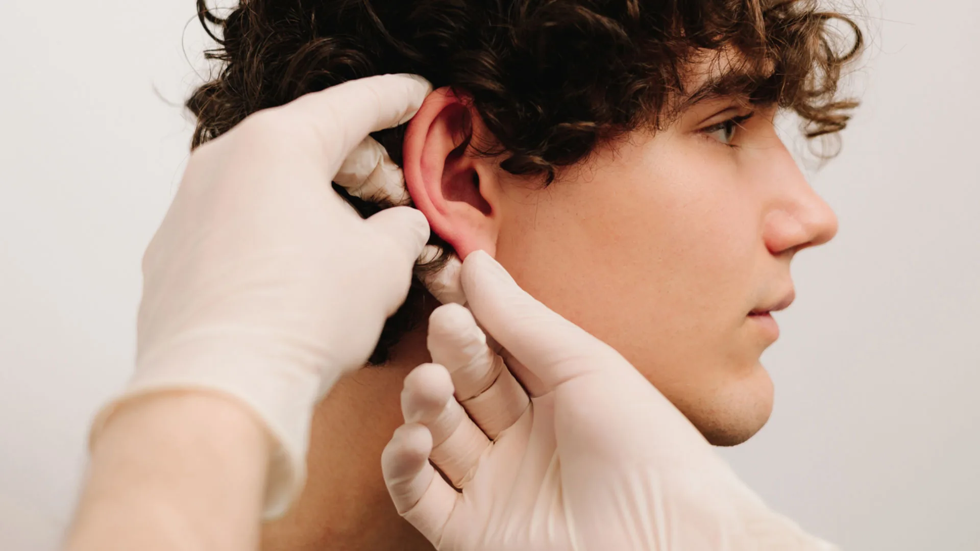 Gloved provider examining a young man's ear
