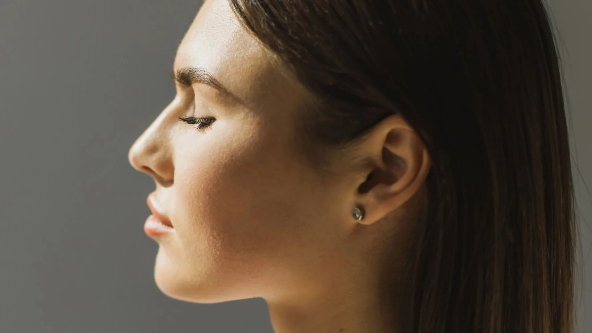 Woman in profile with her hair tucked behind her ear, eyes closed