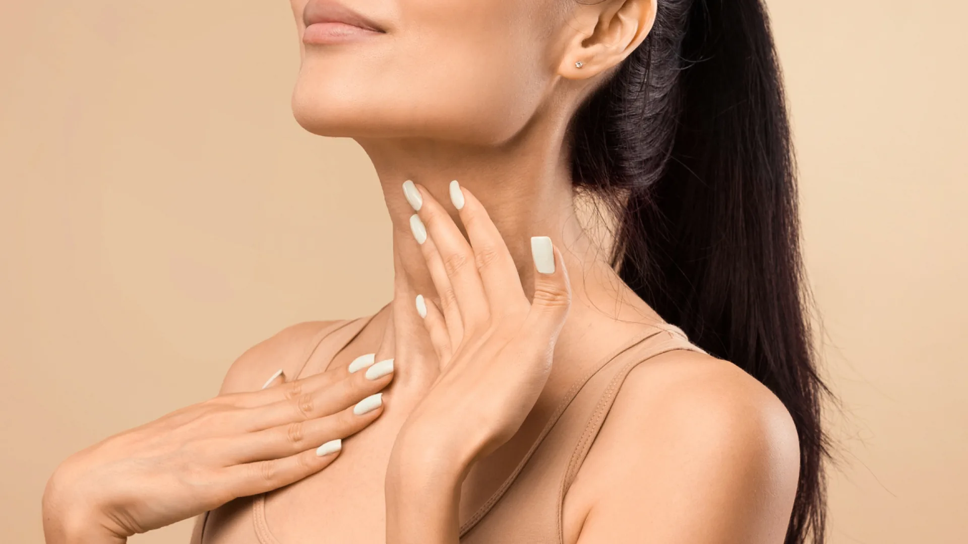 Woman's chin and neck with her hands resting gently along her throat