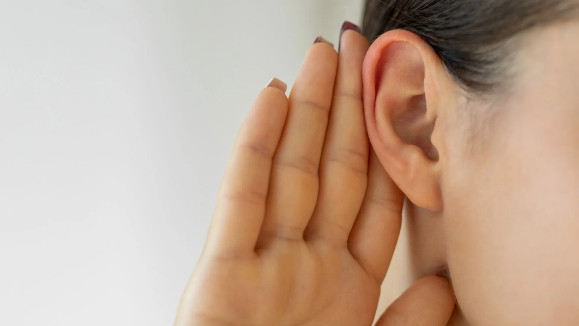 Close-up of a woman cupping her hand behind her ear