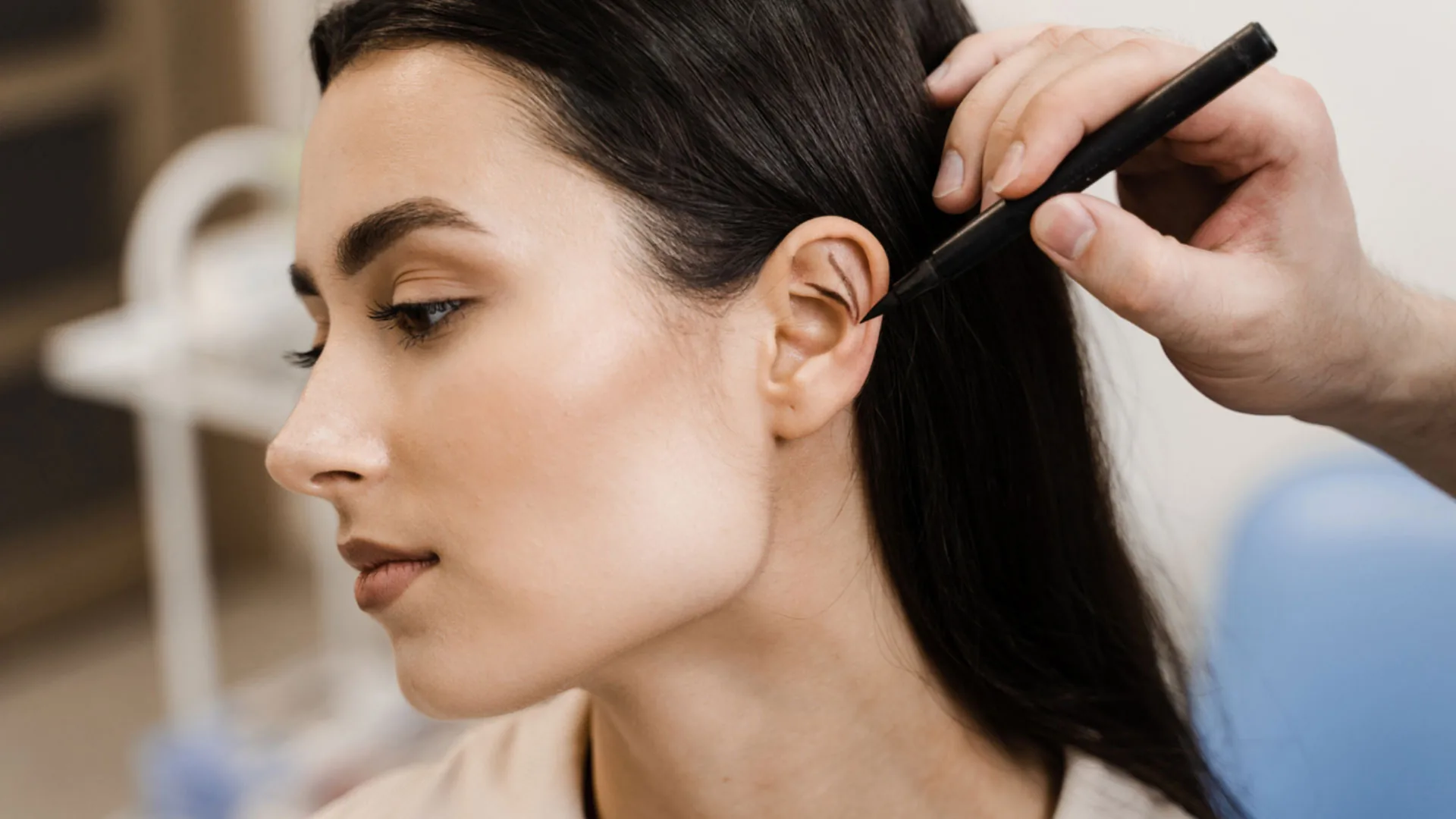 Provider marking a patient's ear with a surgical pen during a consultation