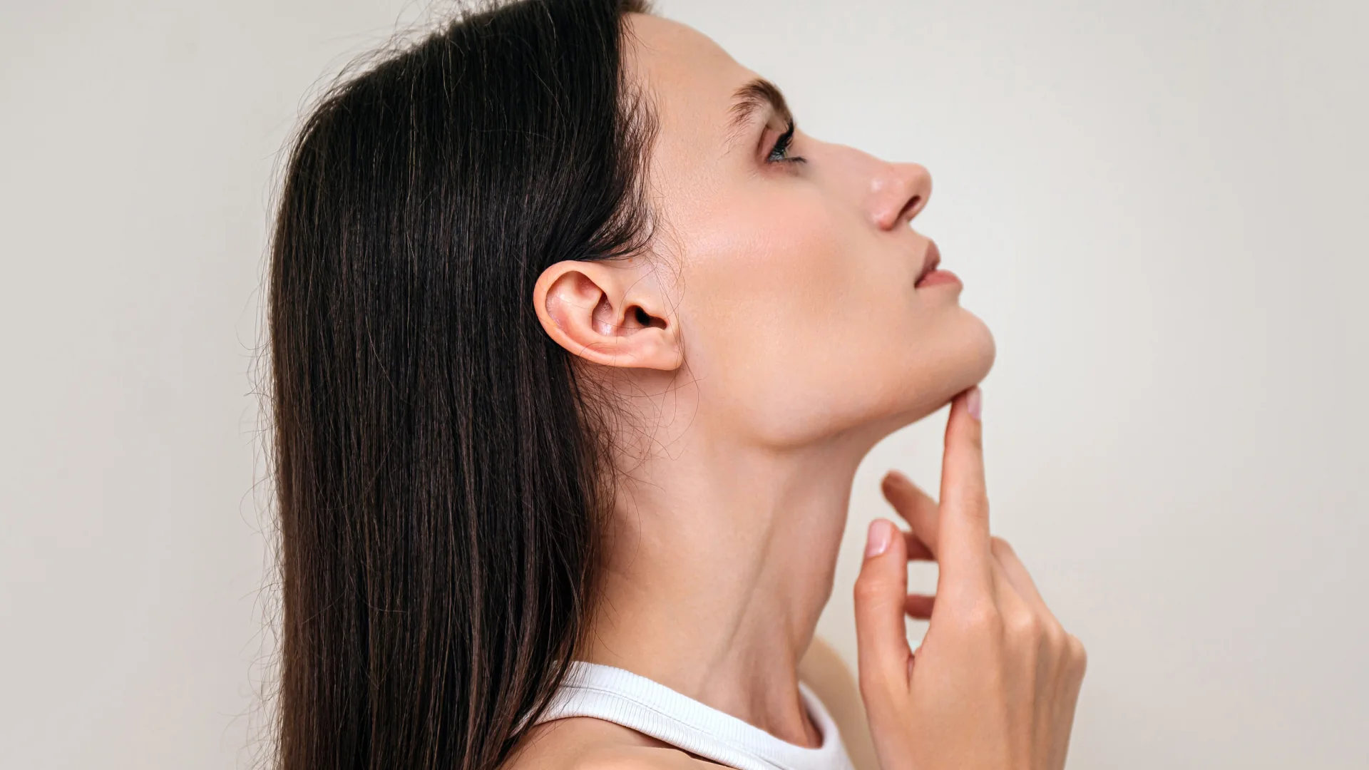 Woman in profile lifting her chin with her fingertips