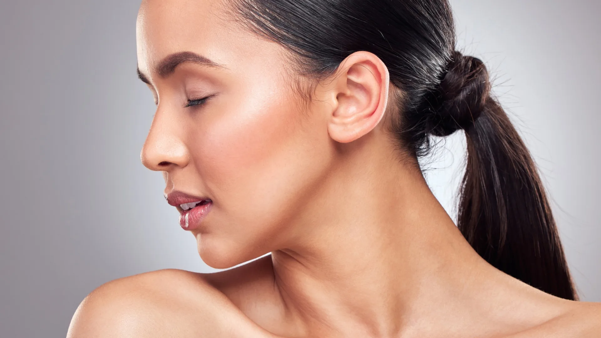 Woman in profile with eyes closed and hair pulled back in a low bun