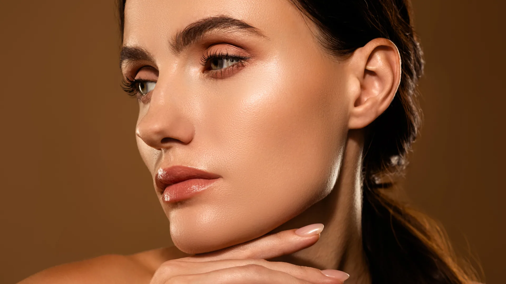 Woman resting her chin on her hand against a warm brown background