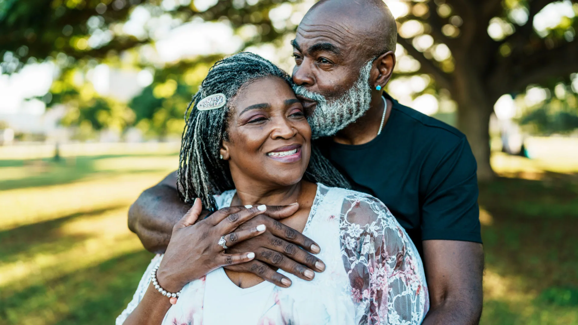 Smiling older couple embracing outdoors under a tree