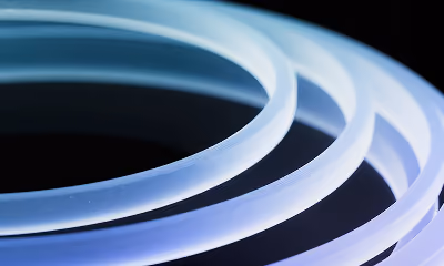 Close-up of glowing flexible neon LED light strips coiled on a dark background.