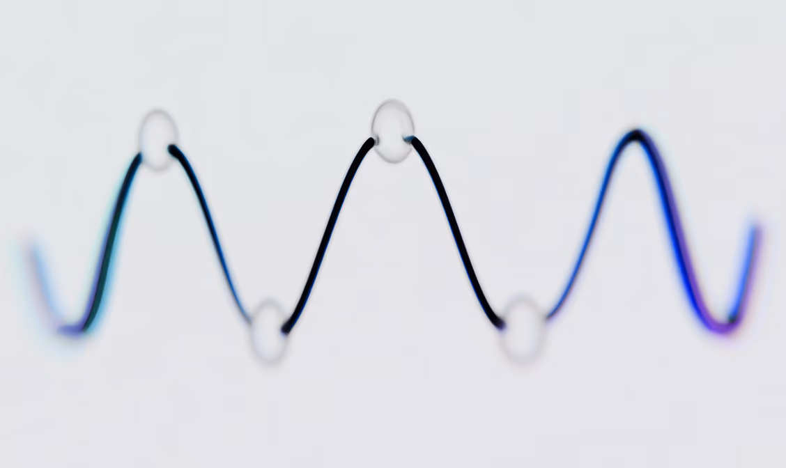 Black wavy line threaded through five transparent beads on a light background.