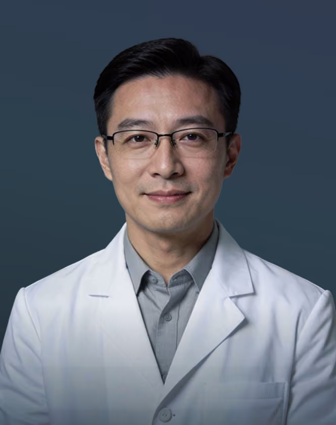 Smiling male doctor wearing glasses and a white coat against a dark background.