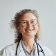 Smiling female doctor with curly hair, glasses, and stethoscope around her neck.