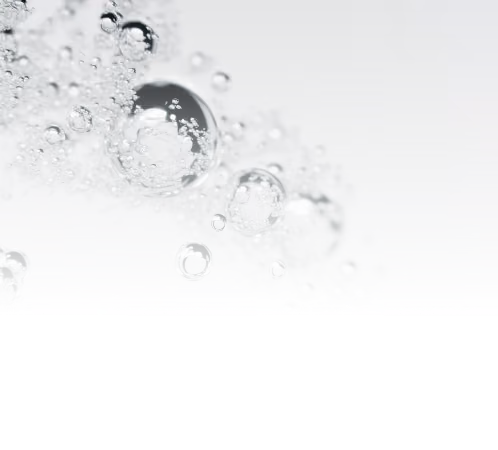 Close-up of multiple clear water bubbles rising against a light background.