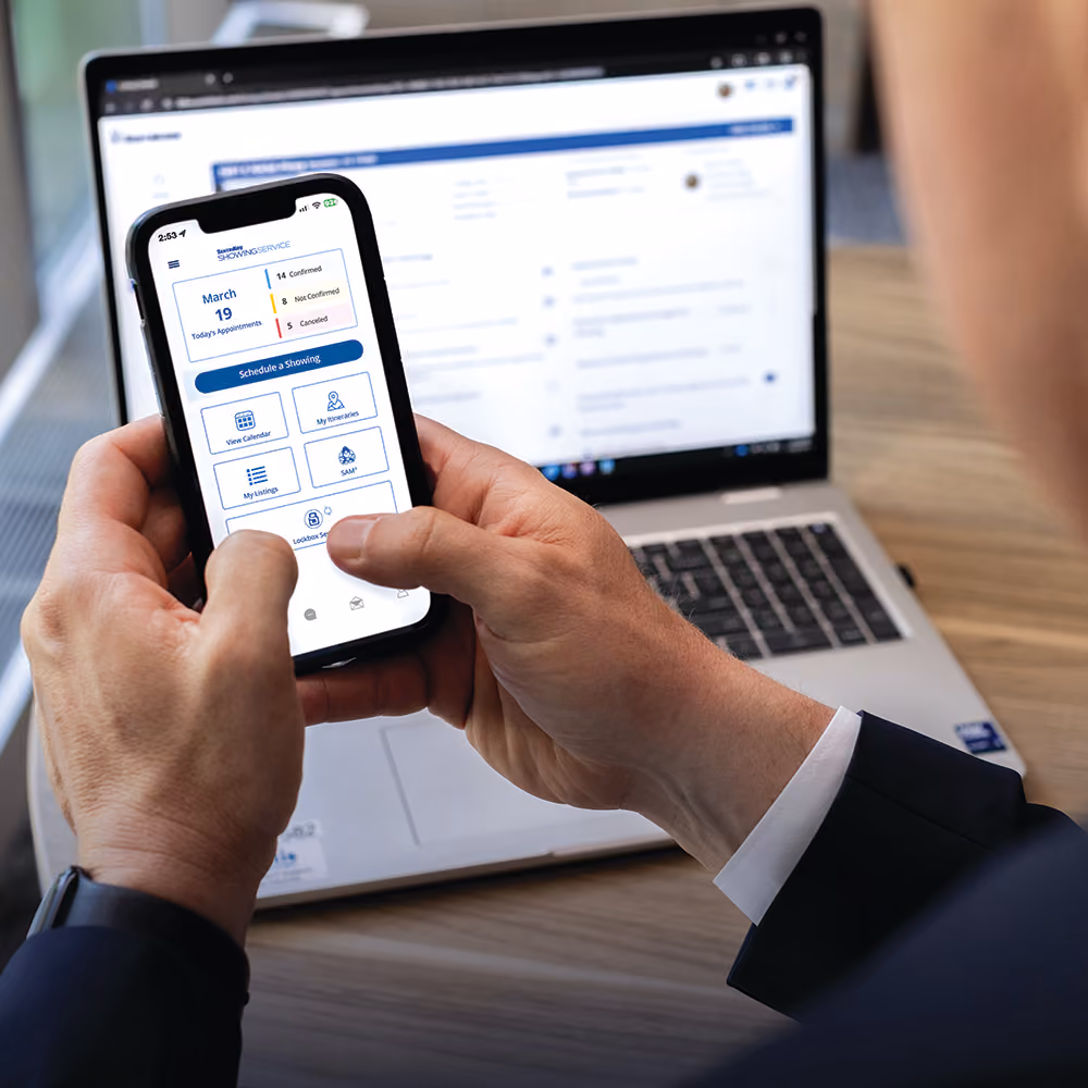 Real estate agent using SentriKey Showing Service on a smartphone and laptop.