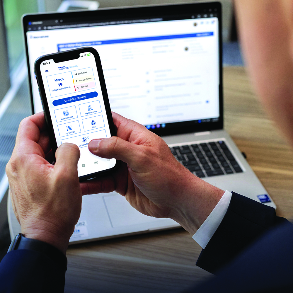 Real estate agent using SentriKey Showing Service on a smartphone and laptop.
