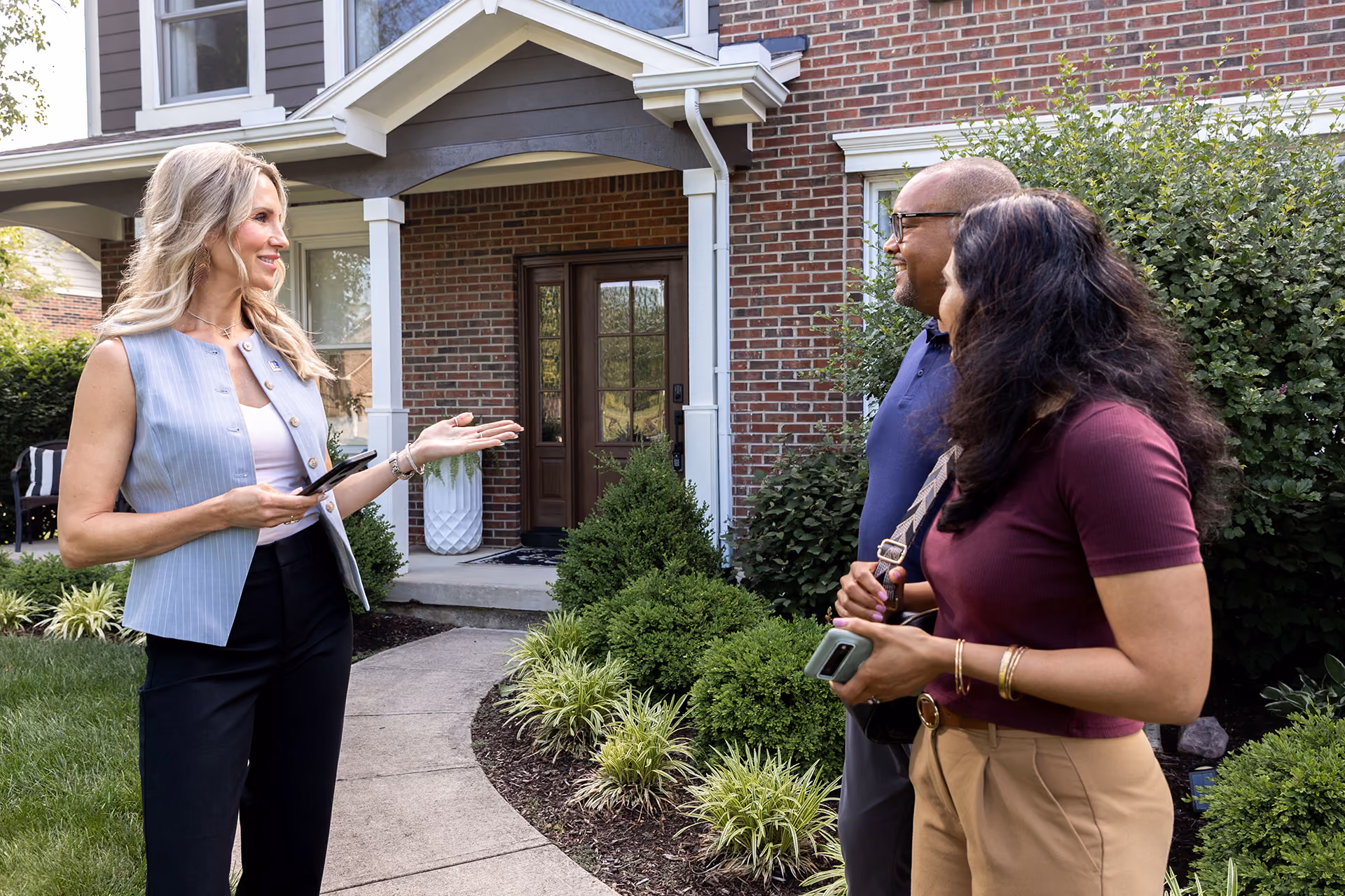 A real estate agent showing a couple a home near the front door.