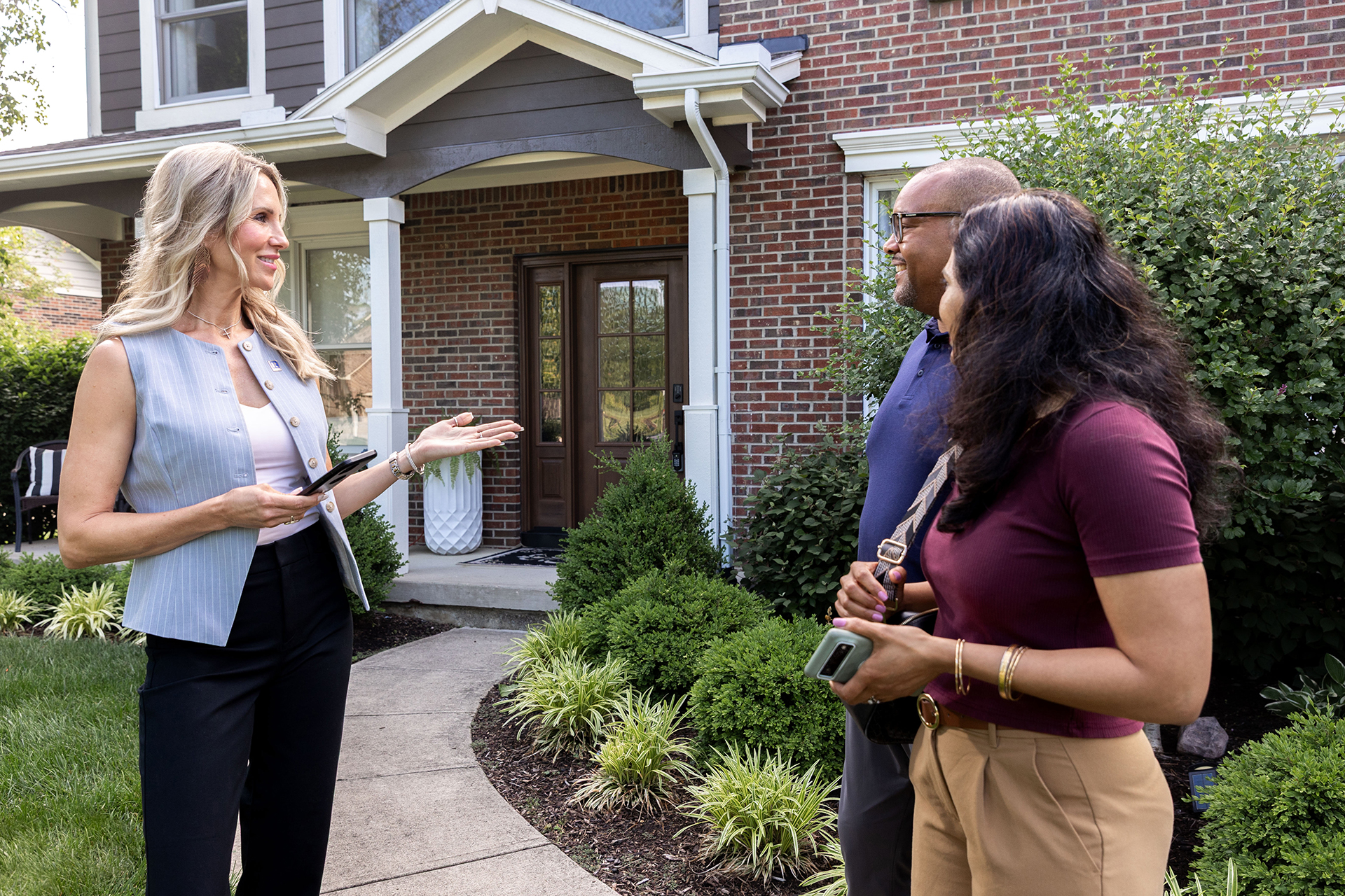 A real estate agent showing a couple a home near the front door.