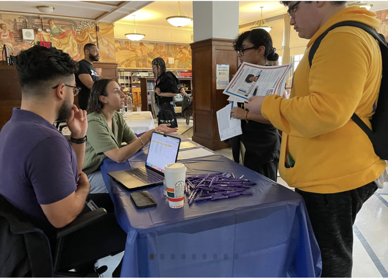 Students speaking with staff at a college or career fair table