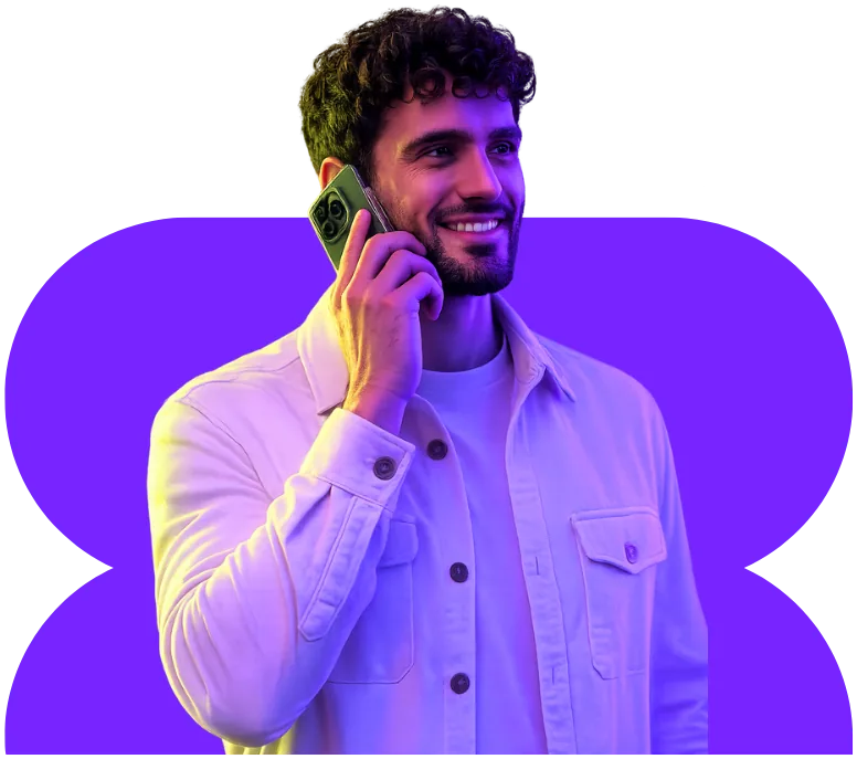 Hombre sonriendo mientras habla por teléfono: IA para telecomunicaciones con agentes de voz de Vozy