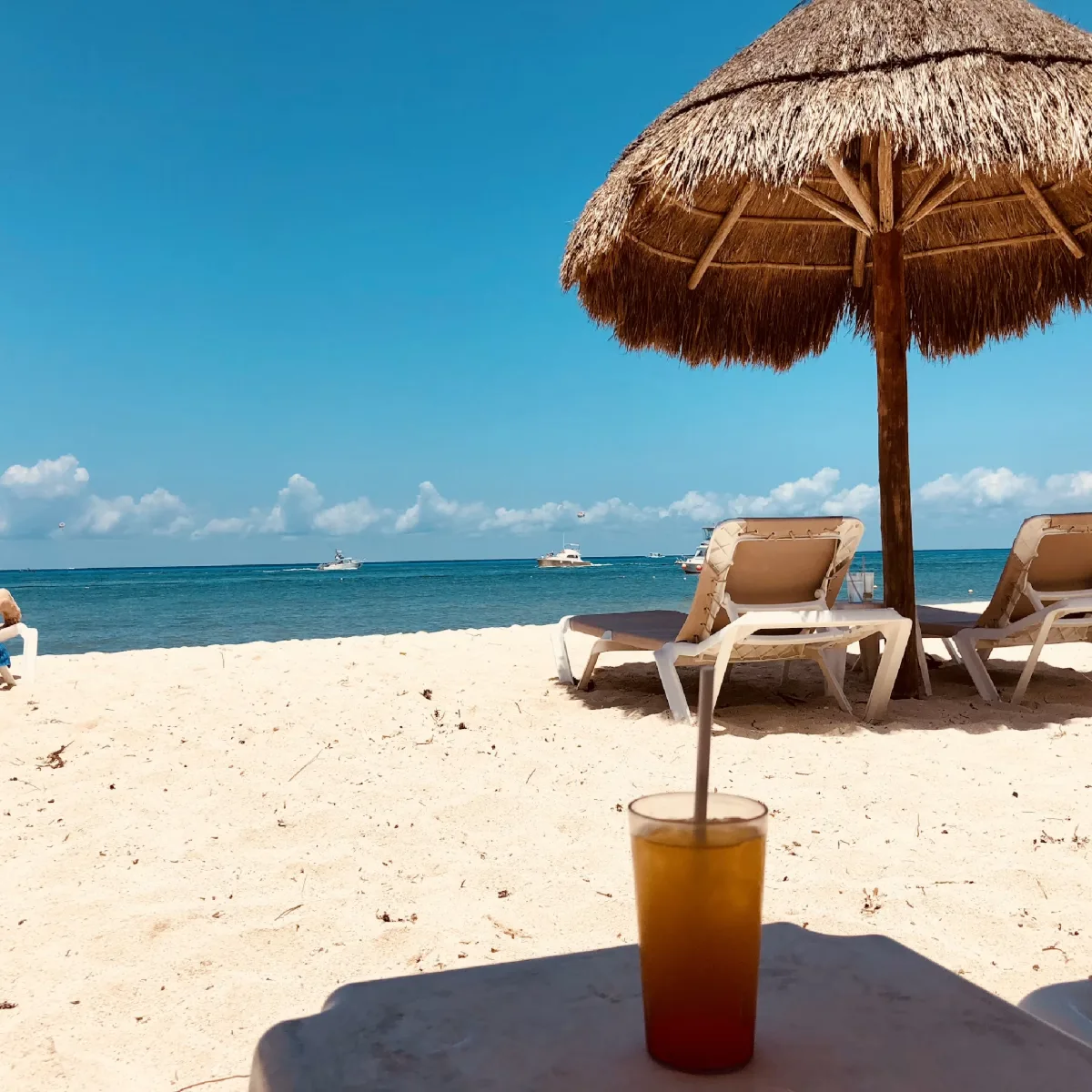 Playa con sombrilla de palma y una bebida frente al mar: caso de éxito de Multivacaciones Decameron con IA