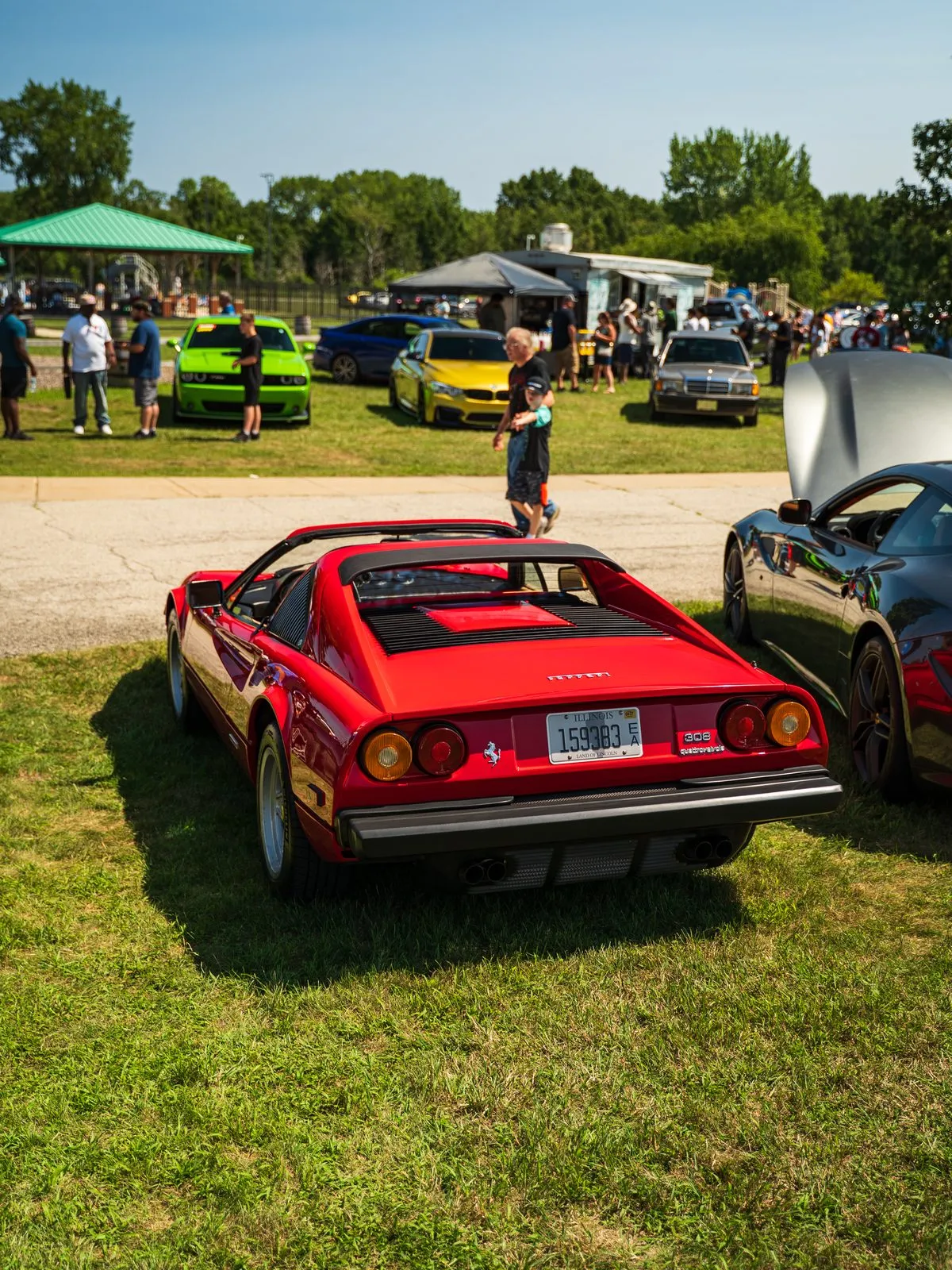 A red Ferrari on the grass with show tents beyond