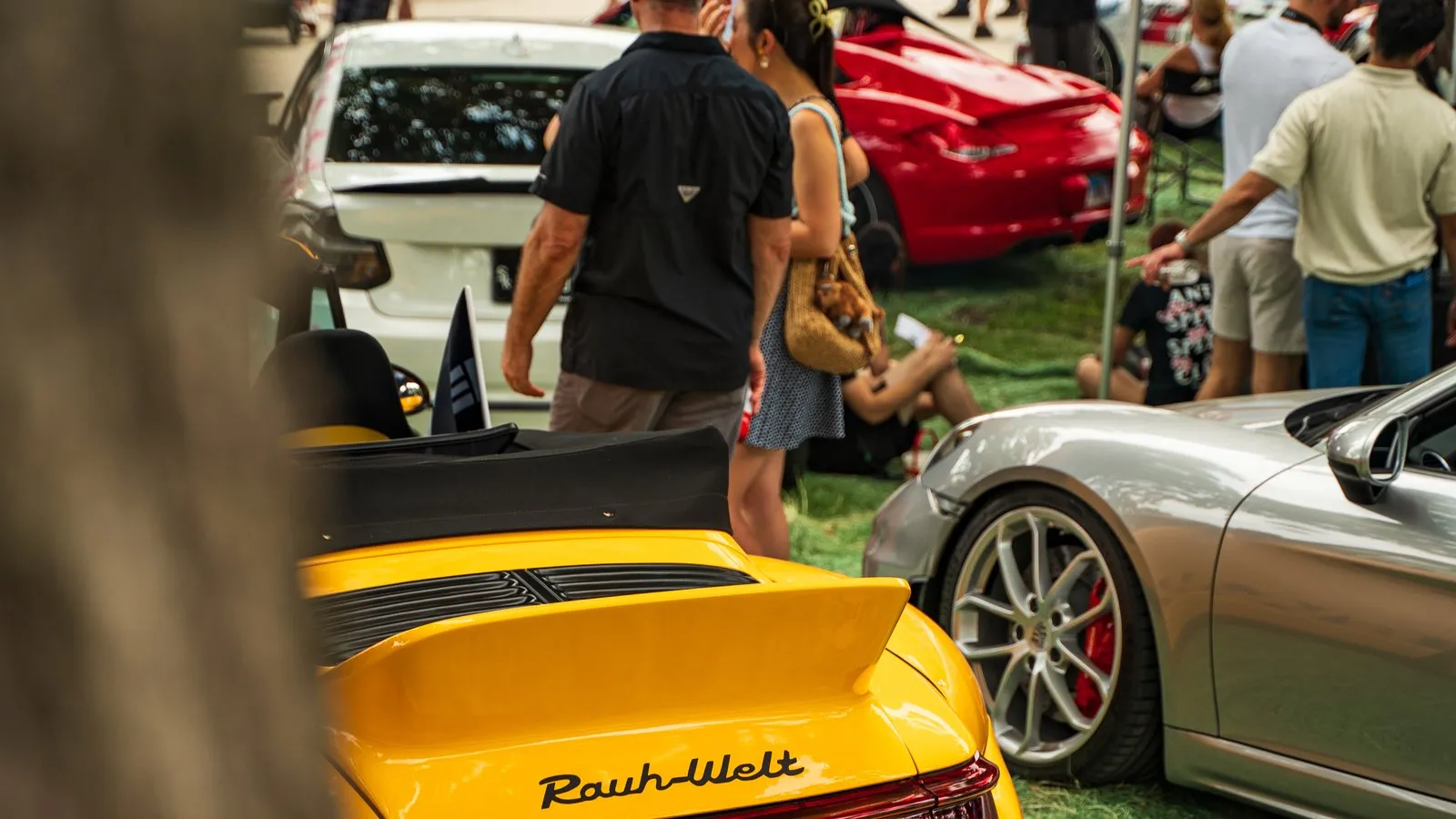 A yellow RWB Porsche among the crowd at a summer car show