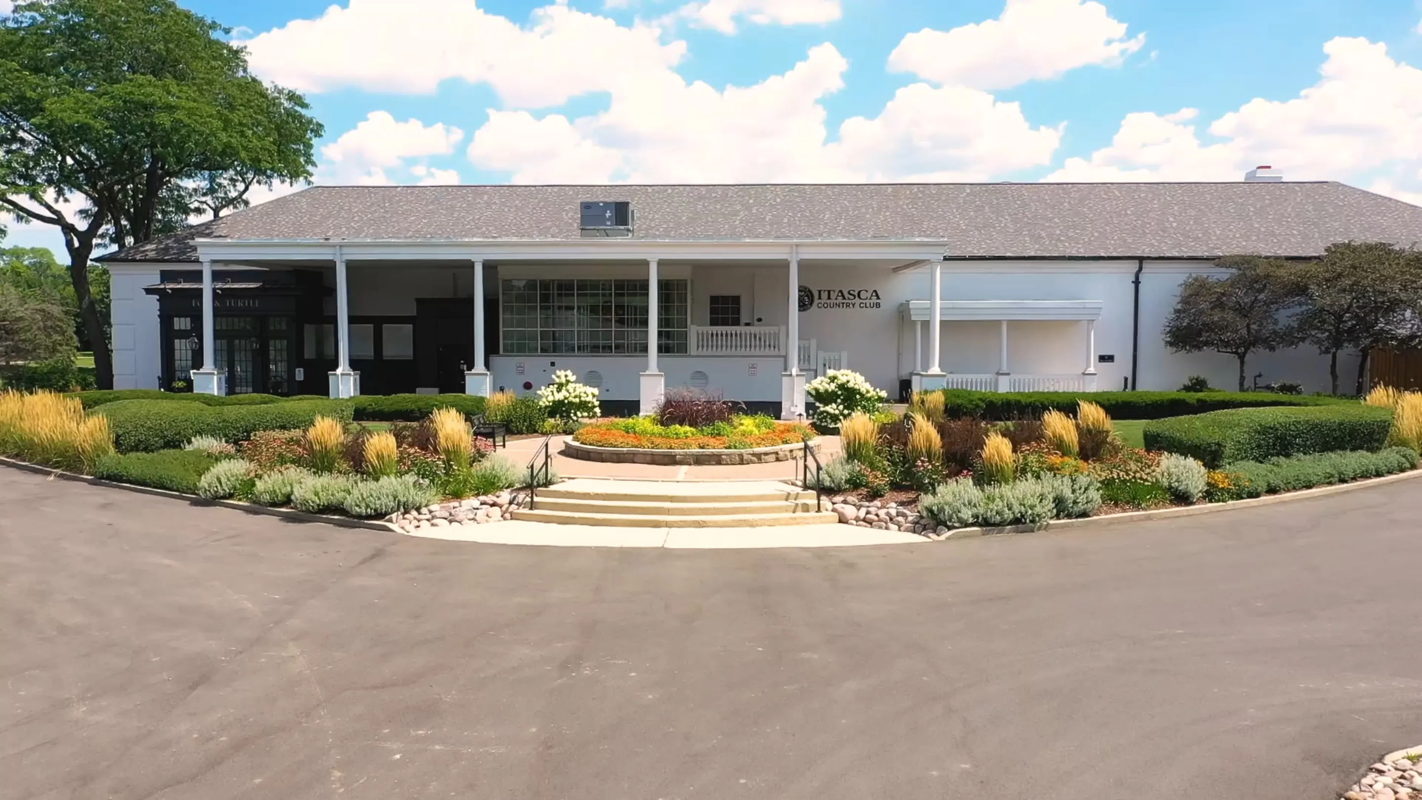 The front entrance of the Itasca Country Club clubhouse, with its white columns and flower beds