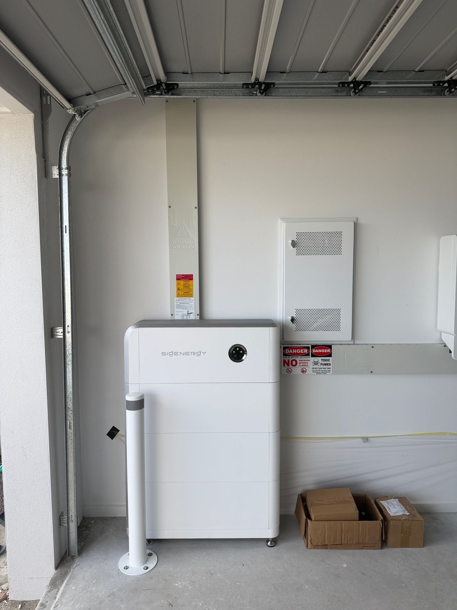 Sigenergy battery with a white safety bollard in a Walloon garage