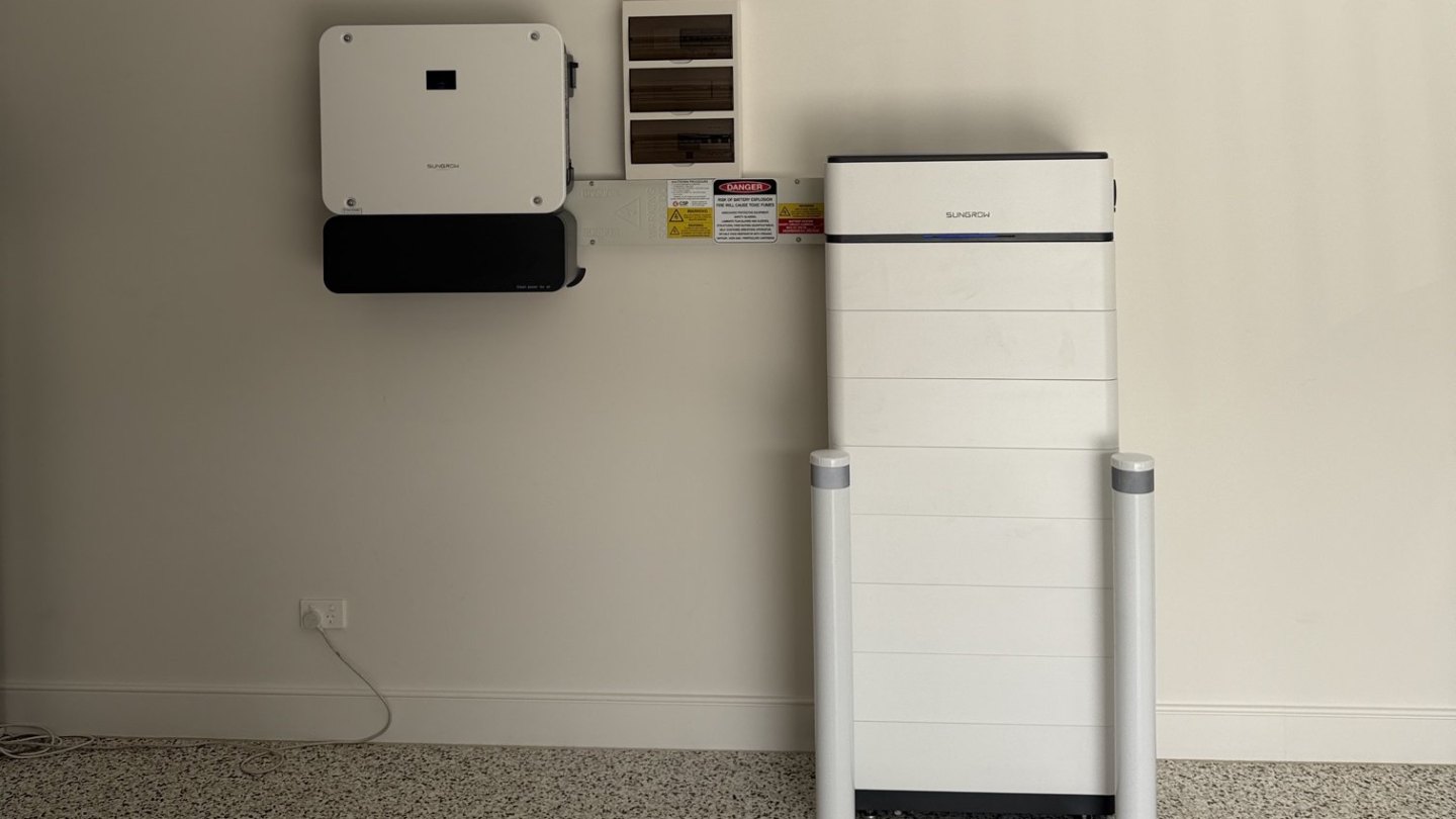 Sungrow hybrid inverter and stacked battery behind safety bollards in a Coorparoo garage