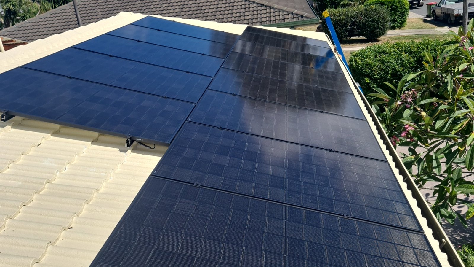 Black solar panels neatly installed in straight rows on a corrugated roof at a Brisbane home by Custom Solar Power