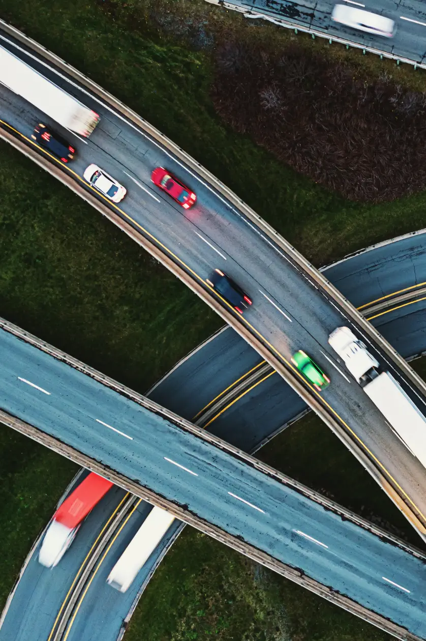 Aerial view of curved highway overpasses with cars and trucks moving on them.